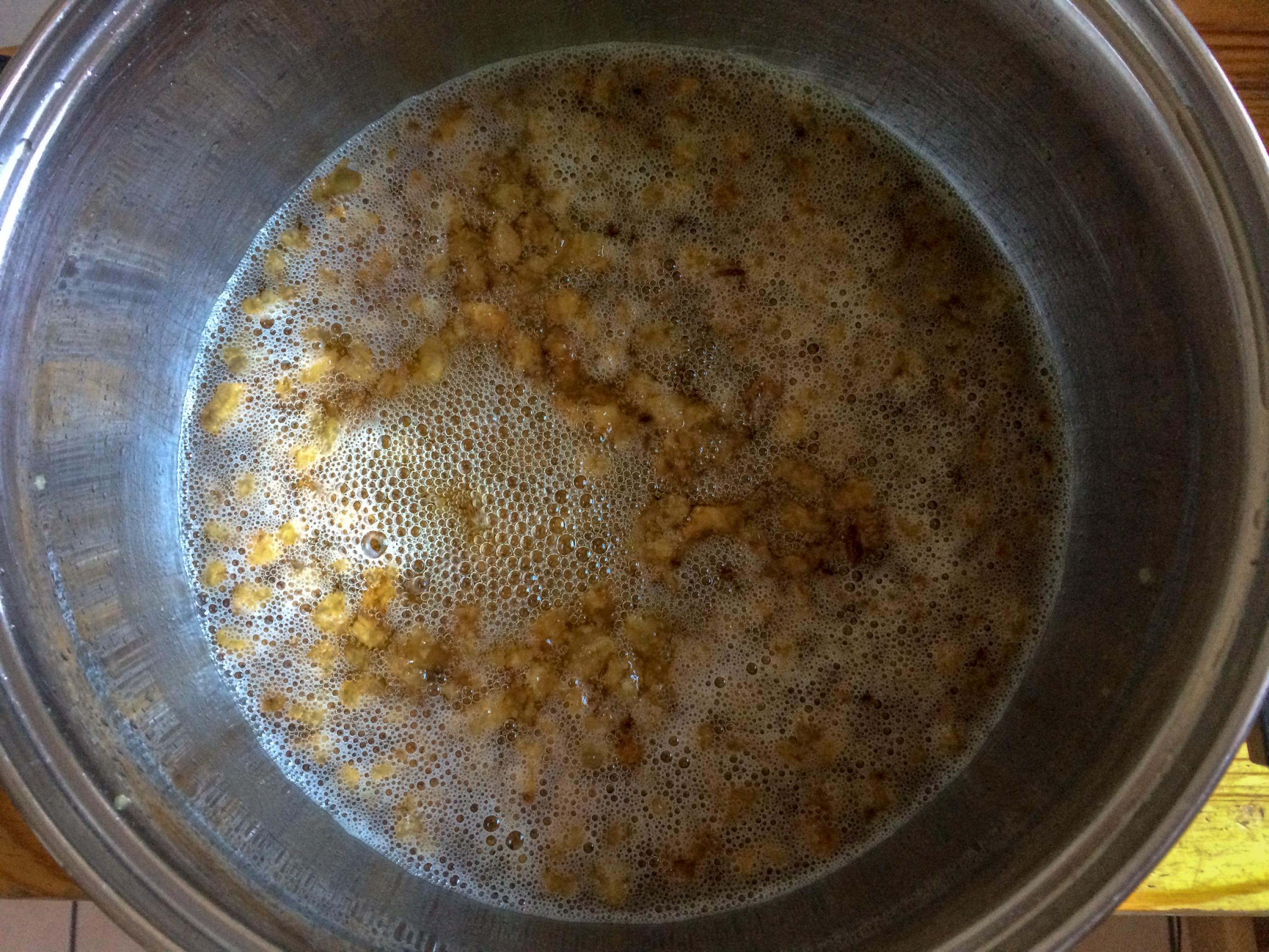 Ein Topf mit einer goldgelben Flüssigkeit, in der kleine braune Würfelchen schwimmen.