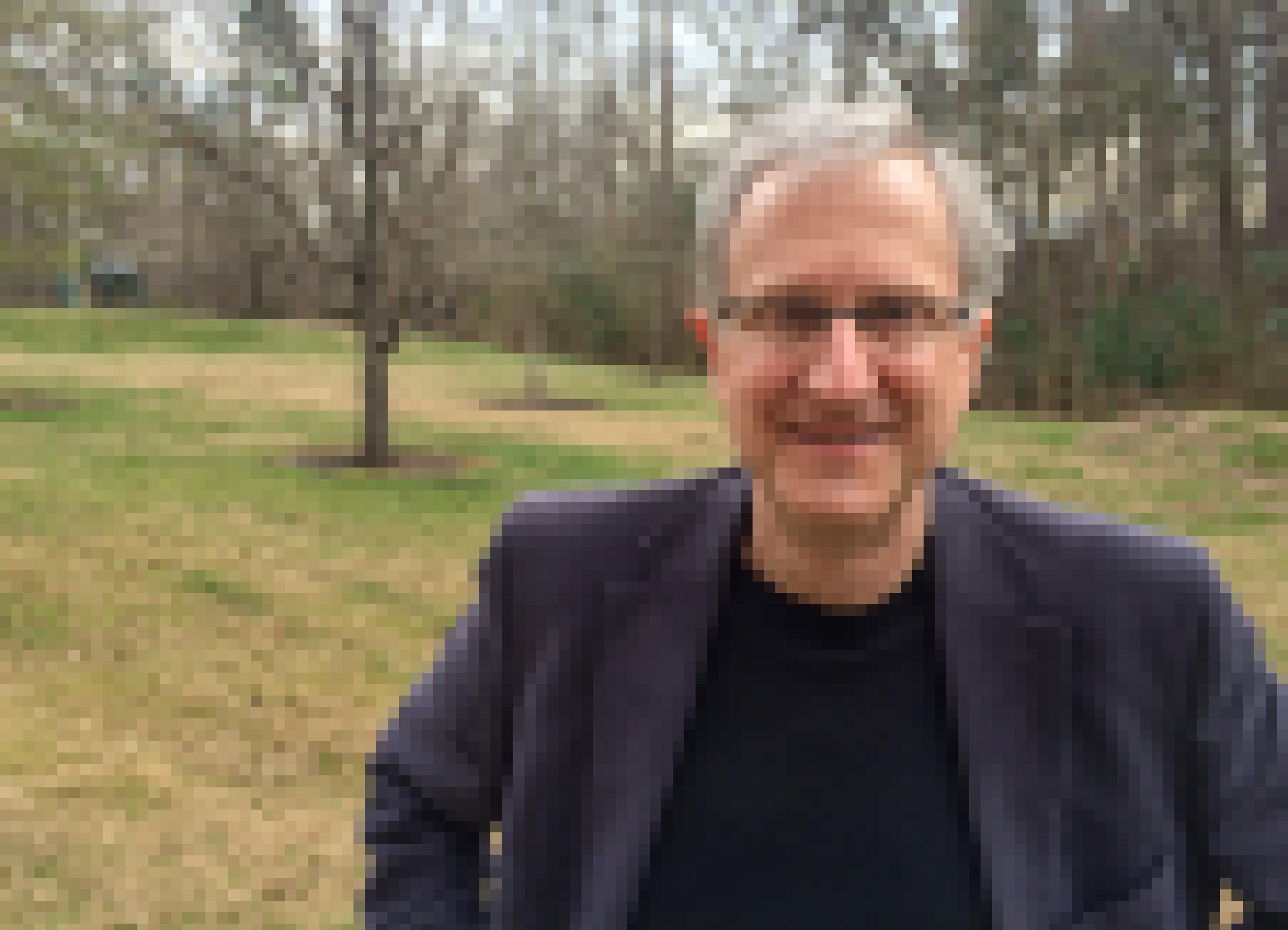 Ein Mann mit grauen Haaren und Brille lächelt in die Kamera.