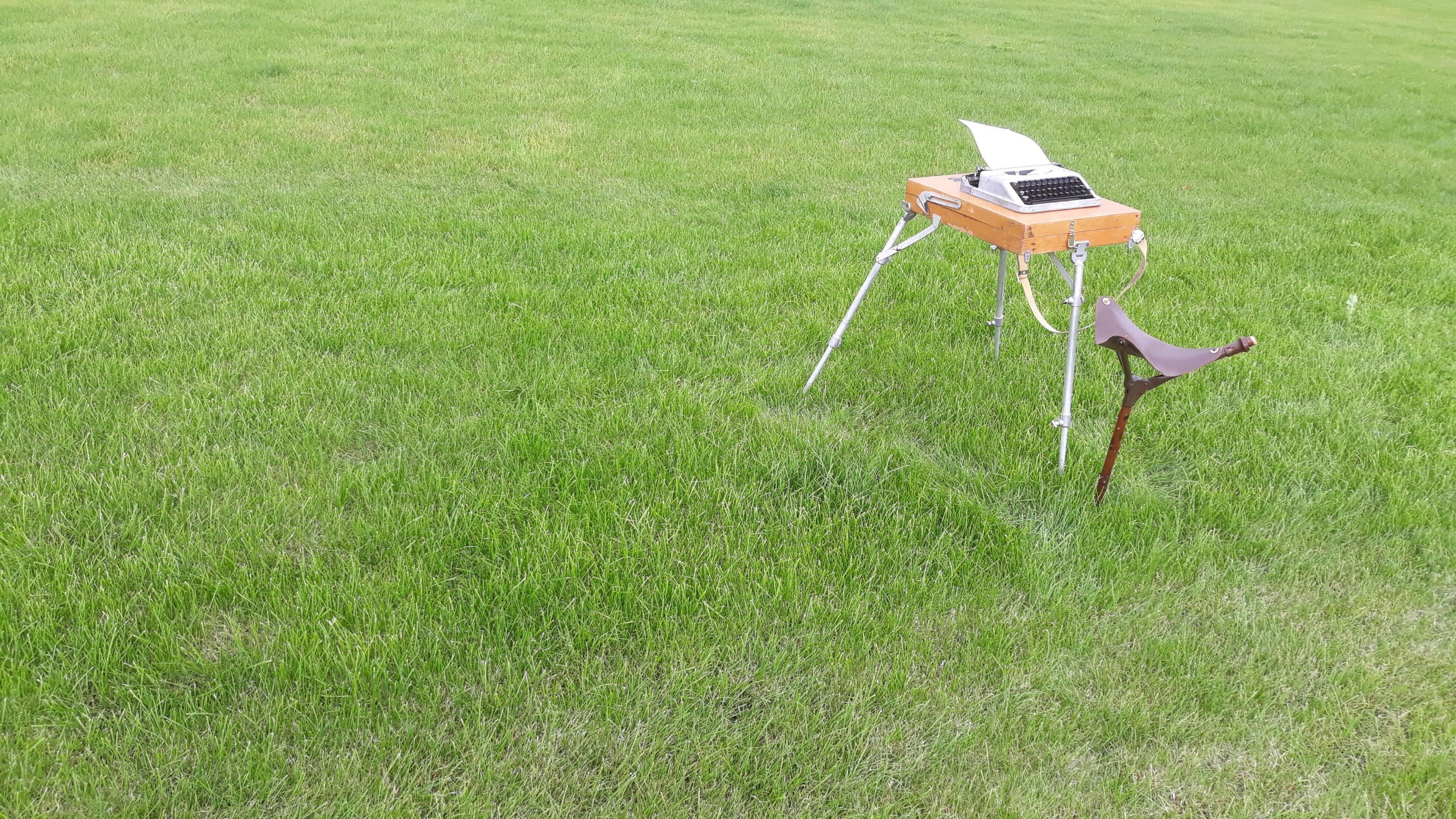 Auf einem Rasen steht der Klappschreibtisch von Autor Gerhard Richter mit Schreibmaschine und Hocker.