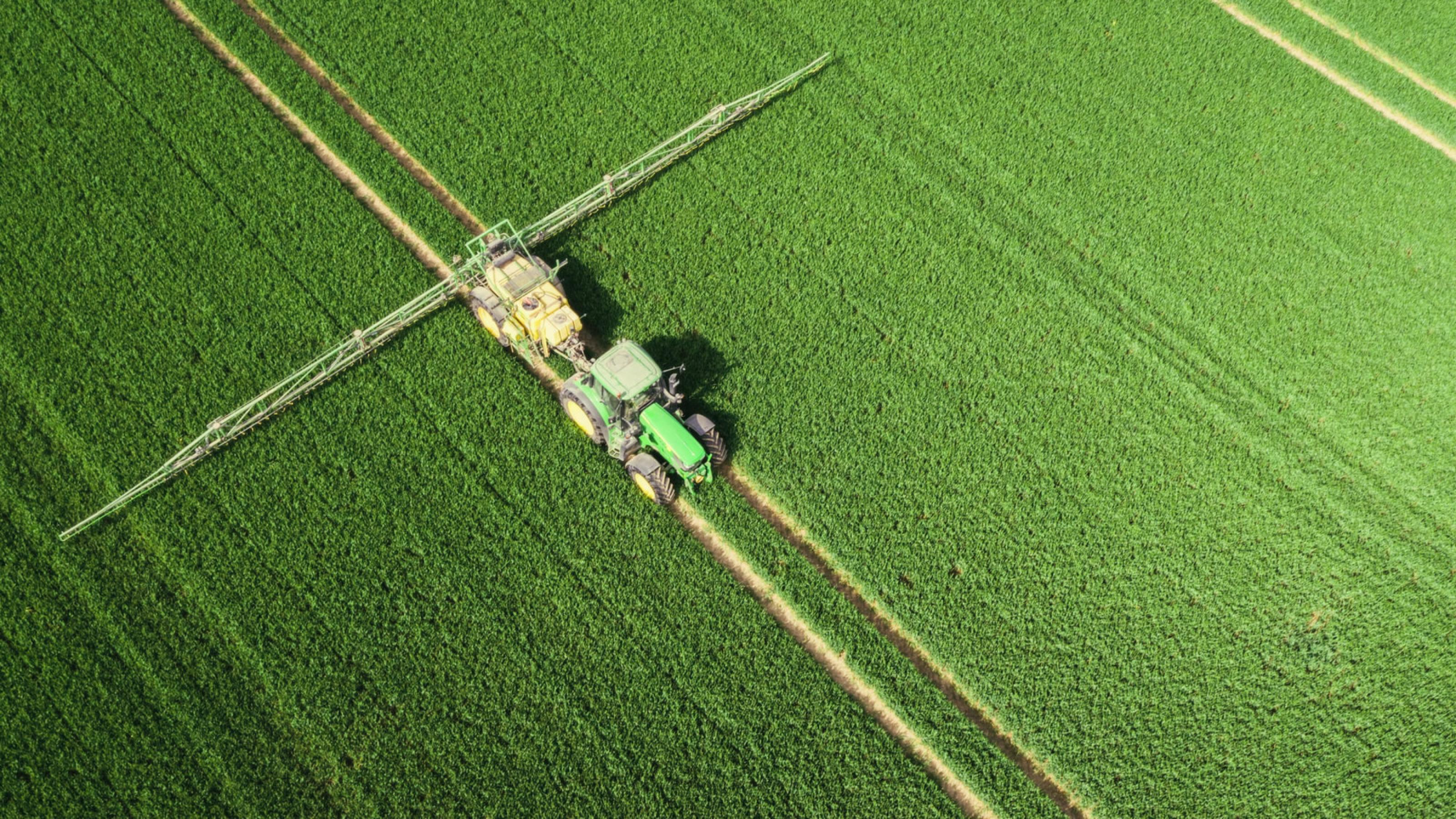 Luftbildaufnahme eines Traktors, der auf einem grünen Feld Dünger ausbringt. Copyright: © 2021 Netflix, Inc.