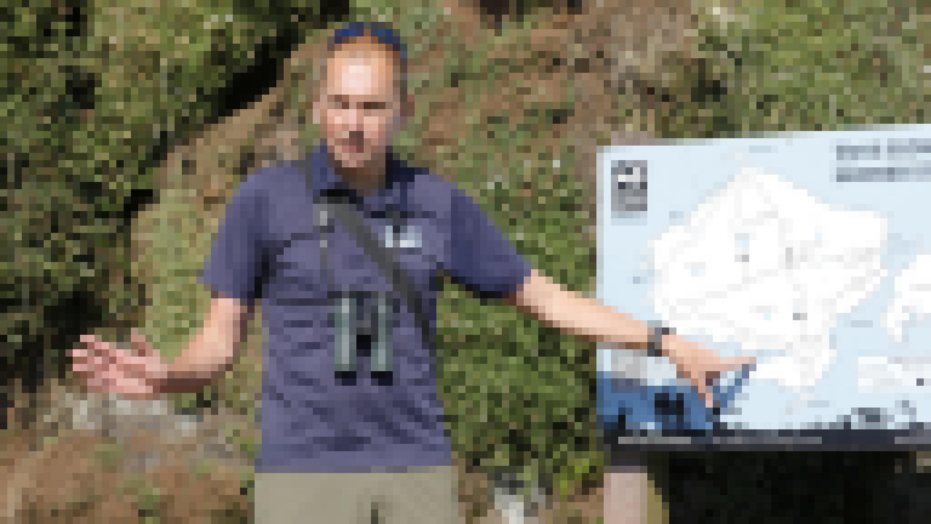 Ein Mann im T-Shirt mit Fernglas vor der Brust deutet auf ein Schild mit einer Karte der Insel Skomer. Rechte: Anne Preger