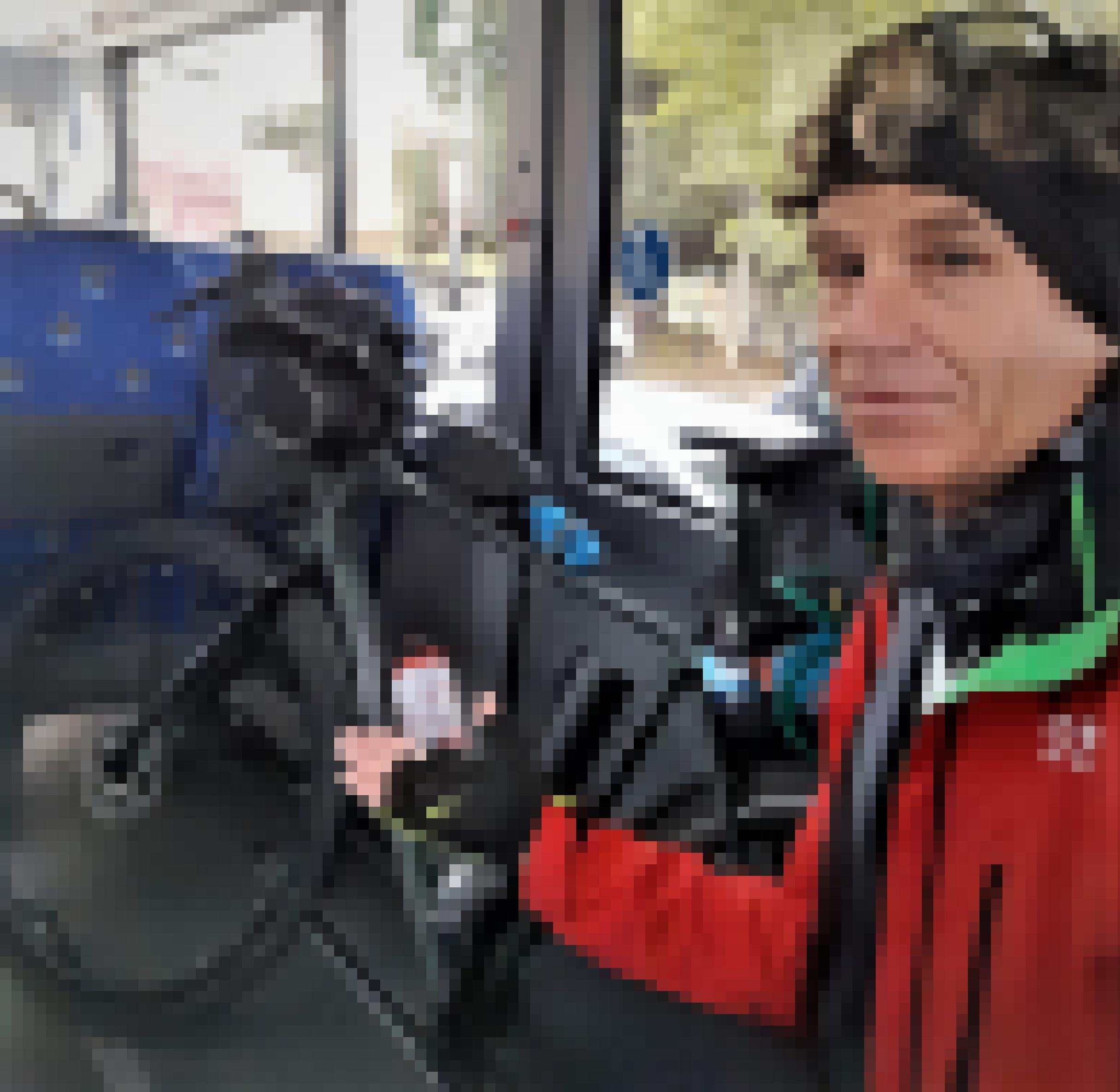 Der Reporter steht in einem Bus und weist mit der Rechten auf sein Fahrrad, das an der rechten Buswand lehnt.