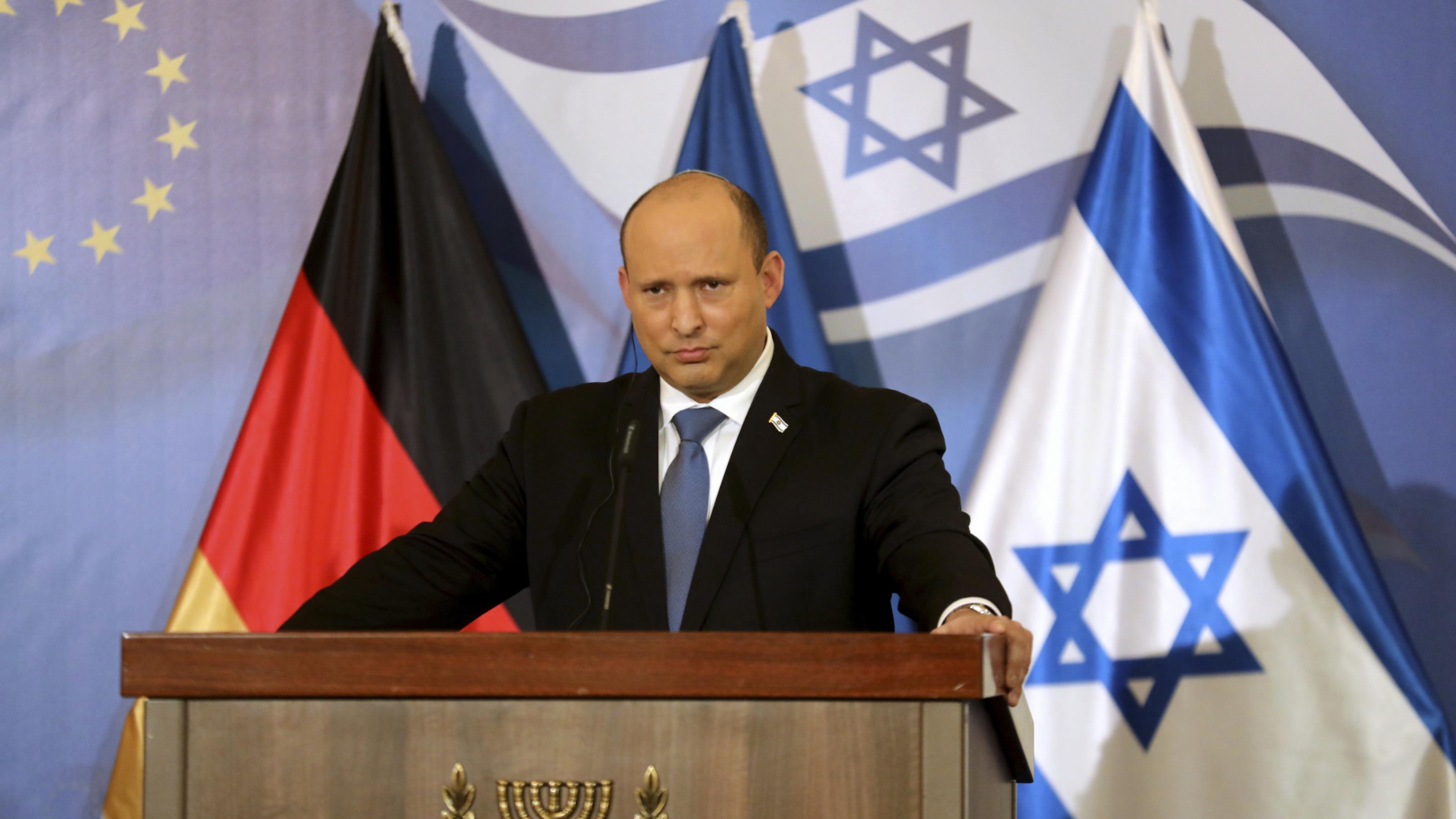 Bennett hinter einem Rednerpult, die Flaggen Israels und Deutschlands im Hintergrund