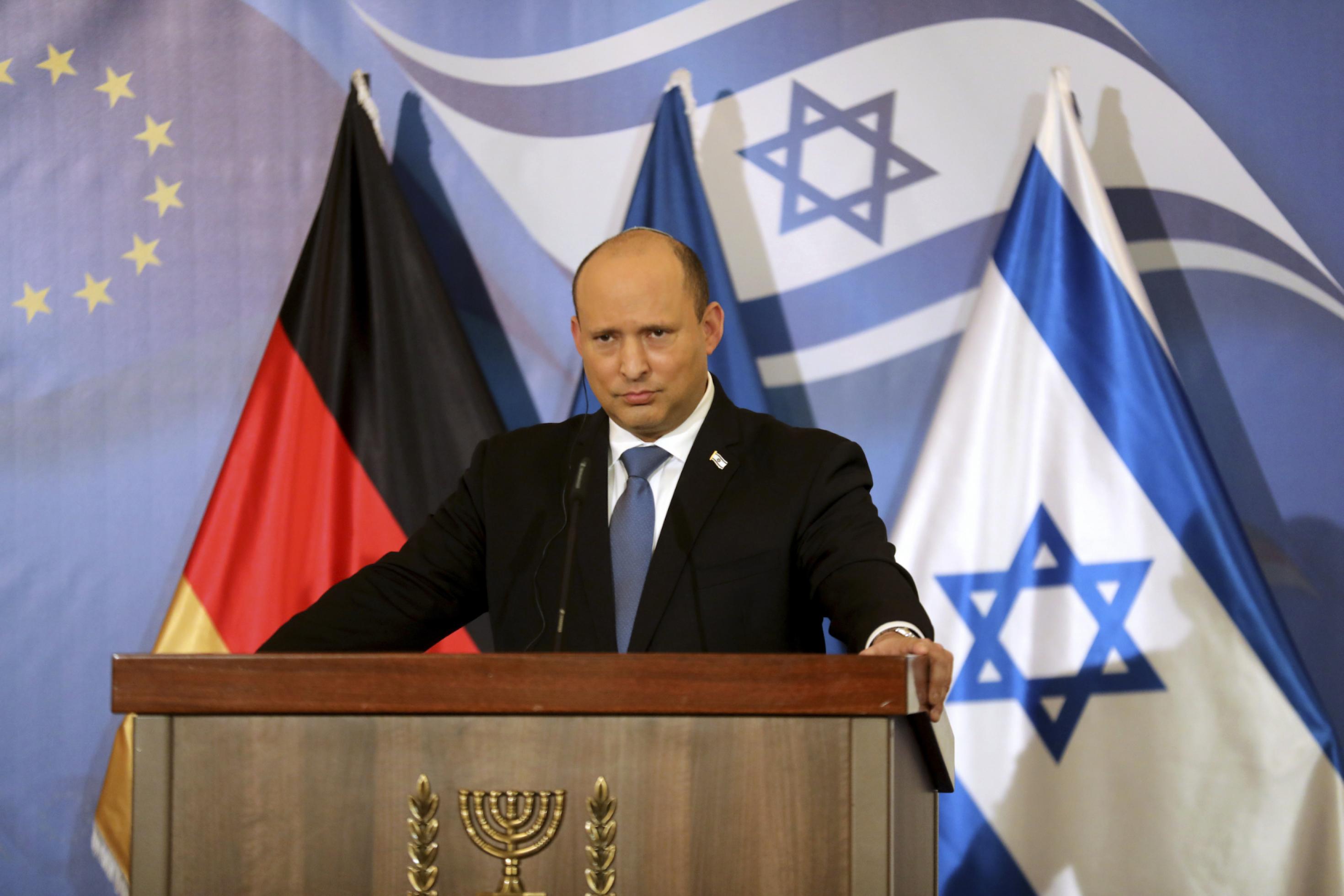 Bennett hinter einem Rednerpult, die Flaggen Israels und Deutschlands im Hintergrund