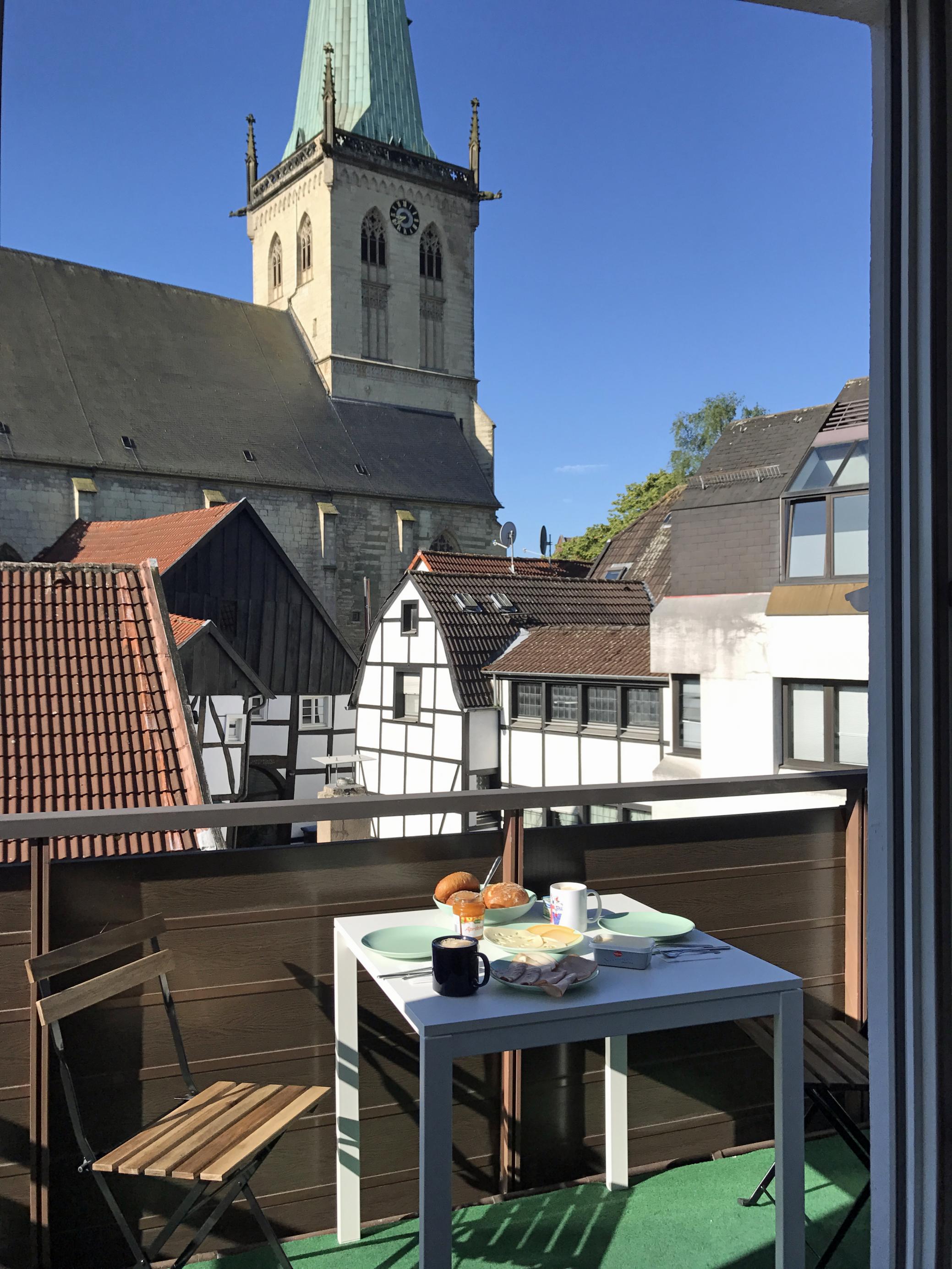 Ein gedeckter Balkontisch und im Hintergrund die Dächer der Altstadt.