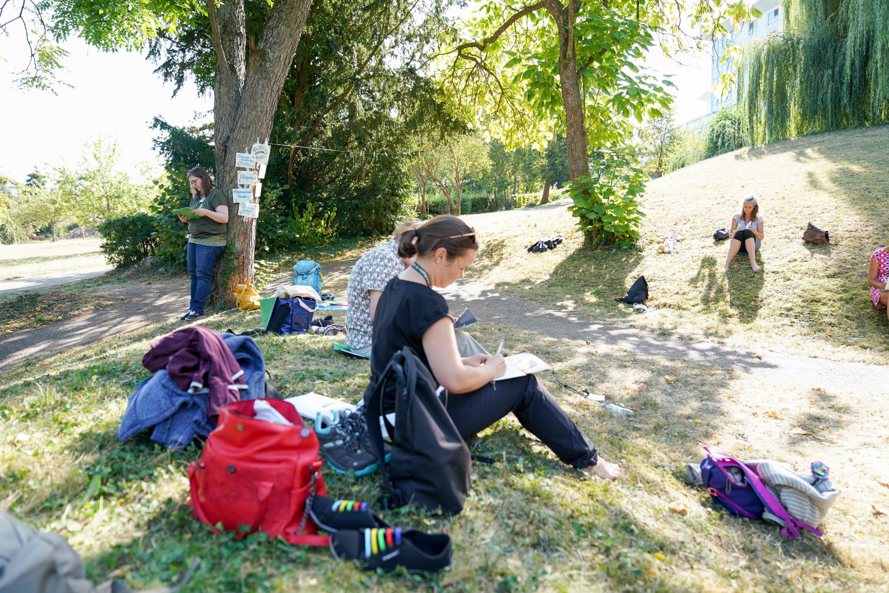 Teilnehmer mit Notizblöcken sitzen auf einer Wiese
