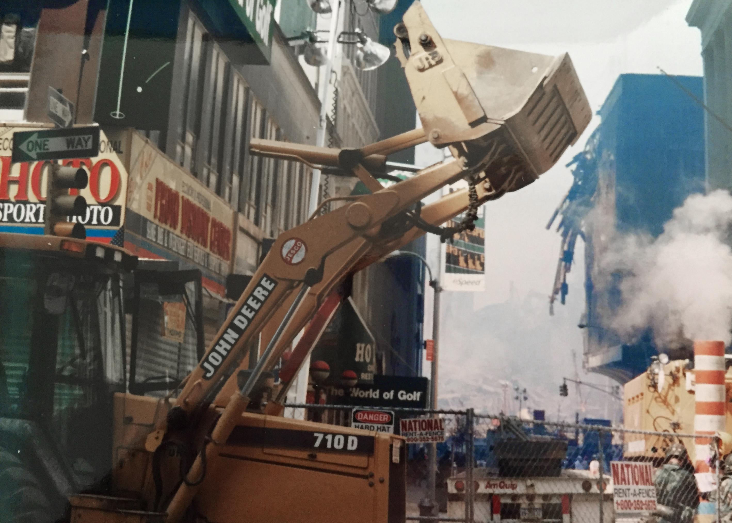 Ein gelber Bagger vor den Trümmern der eingestürzten Trümmer, Asche und Rauch in der Luft