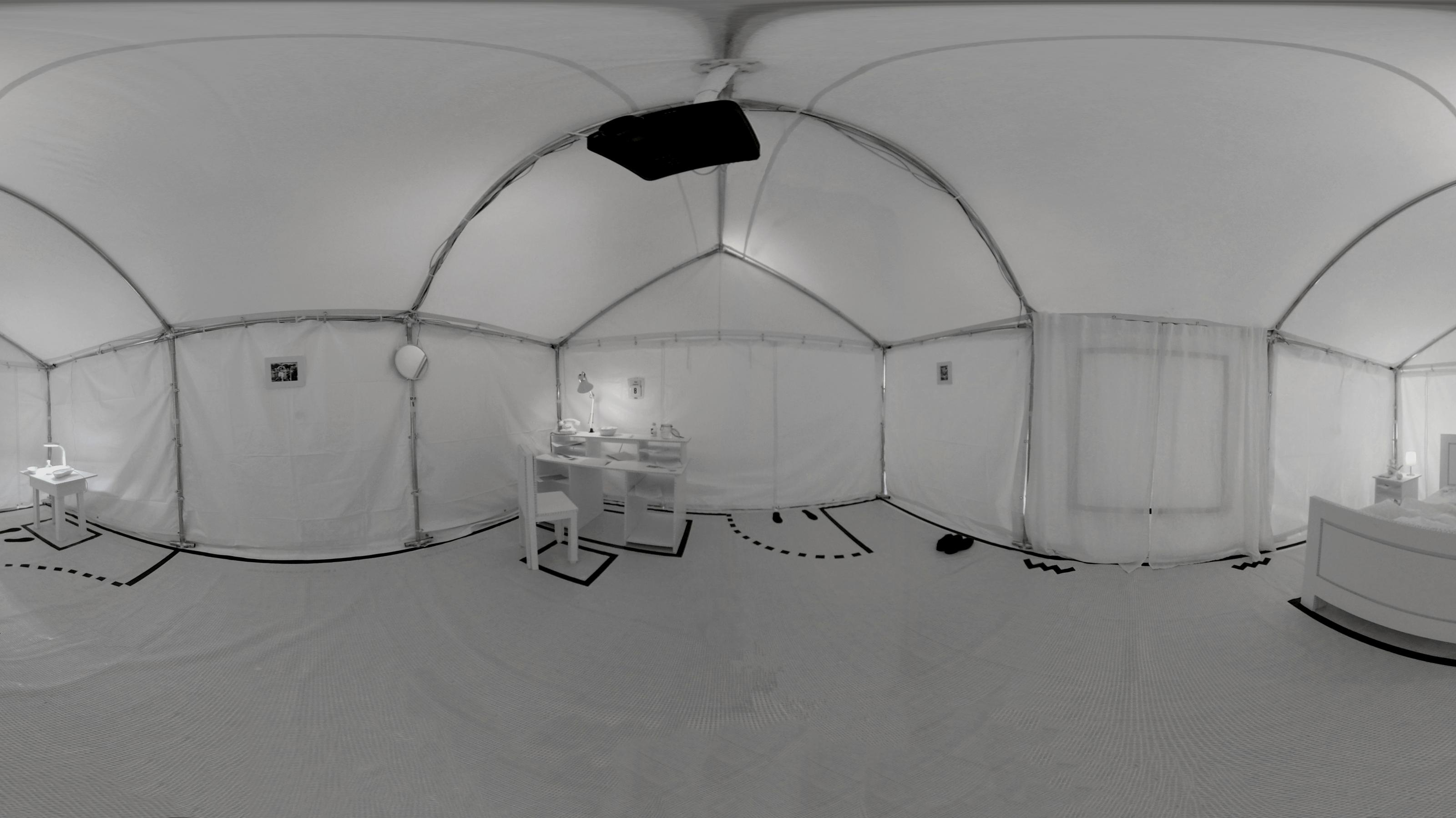 Das Foto zeigt perspektivisch verzerrt die 360-Grad-Rundumsicht eines weißen Raumes. Schwarze Linien auf dem Boden deuten Türen an und weitere Räume. Im Fokus stehen Alan Turings Schreibtisch, sein Bett und seine „Alptraumkammer“, wo er experimentierte.