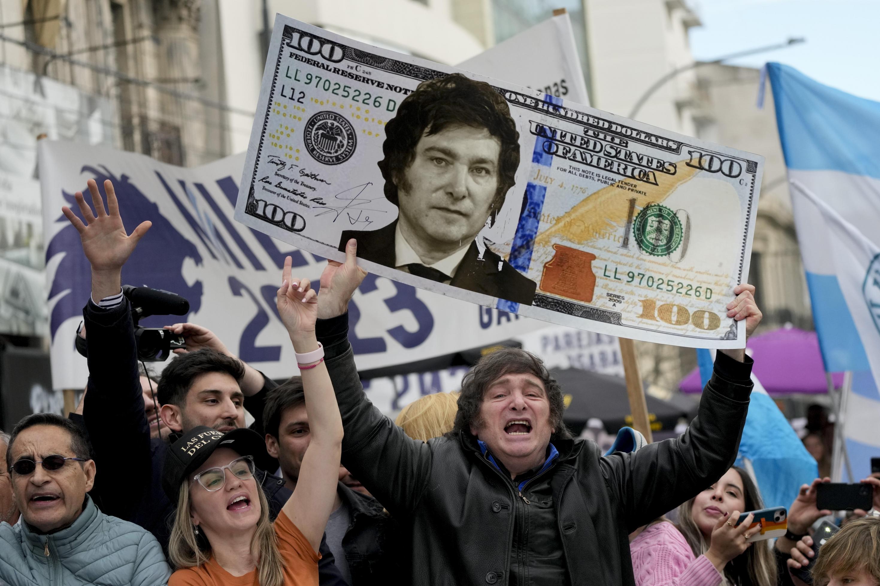 Presidential hopeful of the Liberty Advances coalition Javier Milei, holds up a giant cardboard depicting a U.S. 100 banknote emblazoned with an image of his face, during a rally in La Plata, Argentina, Tuesday, Sept. 12, 2023. The country's economic travails have bolstered Milei, who wants to replace the peso with the dollar, and says that Argentina's Central Bank should be abolished. (AP Photo/Natacha Pisarenko)