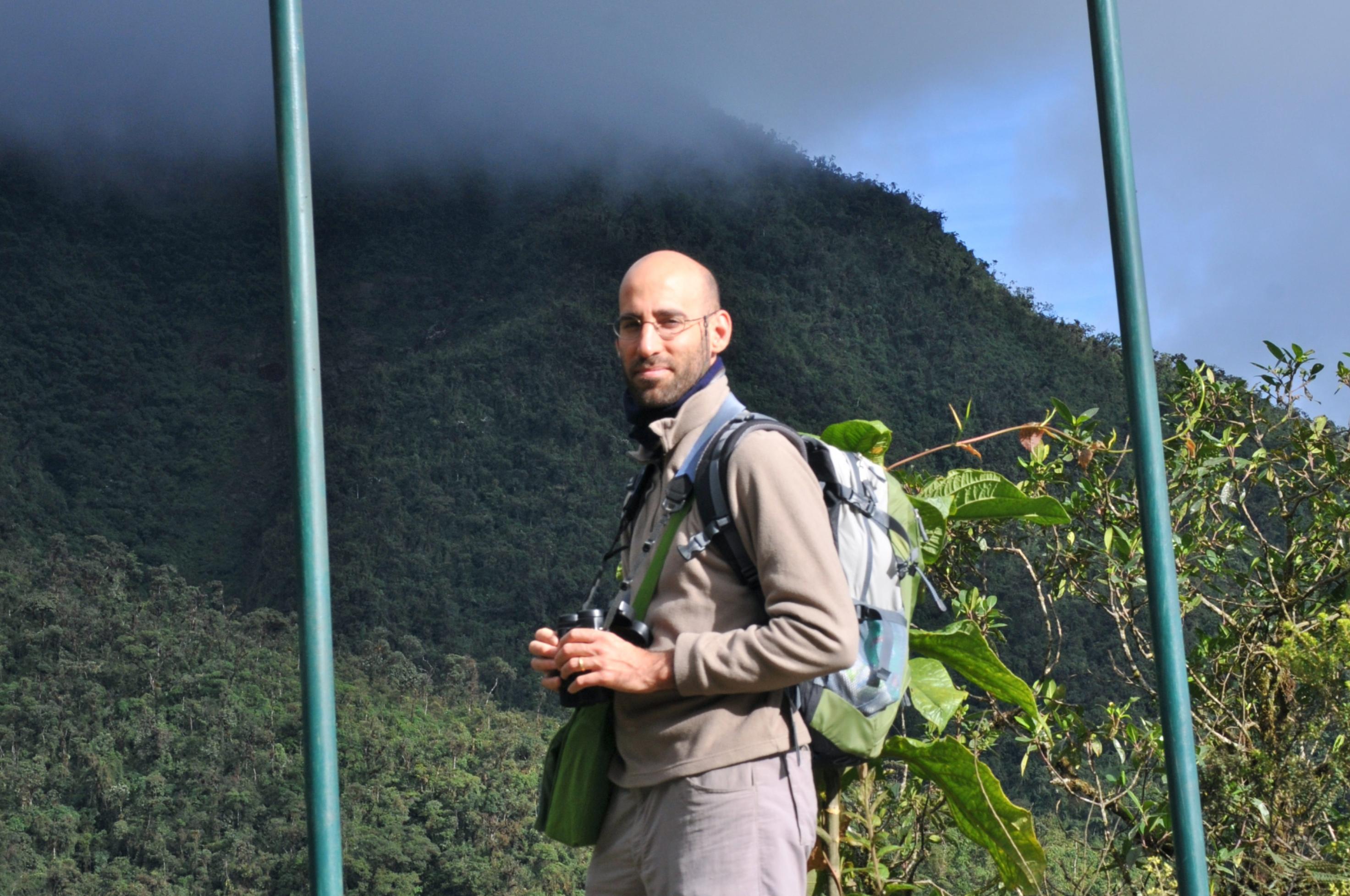 Ariel Brunner mit einem Fernglas in der Hand auf einer Wiese in Ecuador