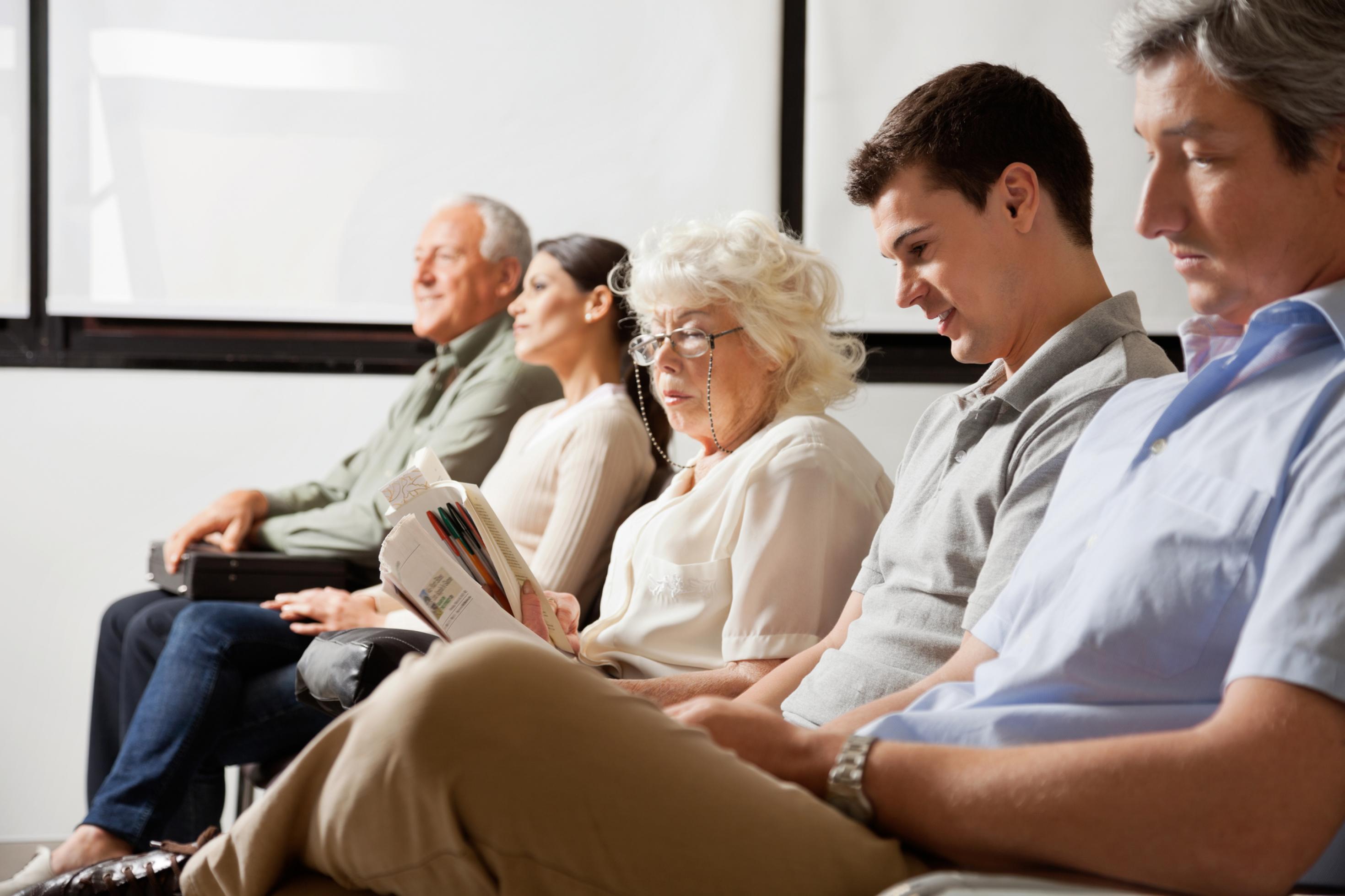 Fünf Menschen unterschiedlichen Alters sitzen in einem Wartezimmer