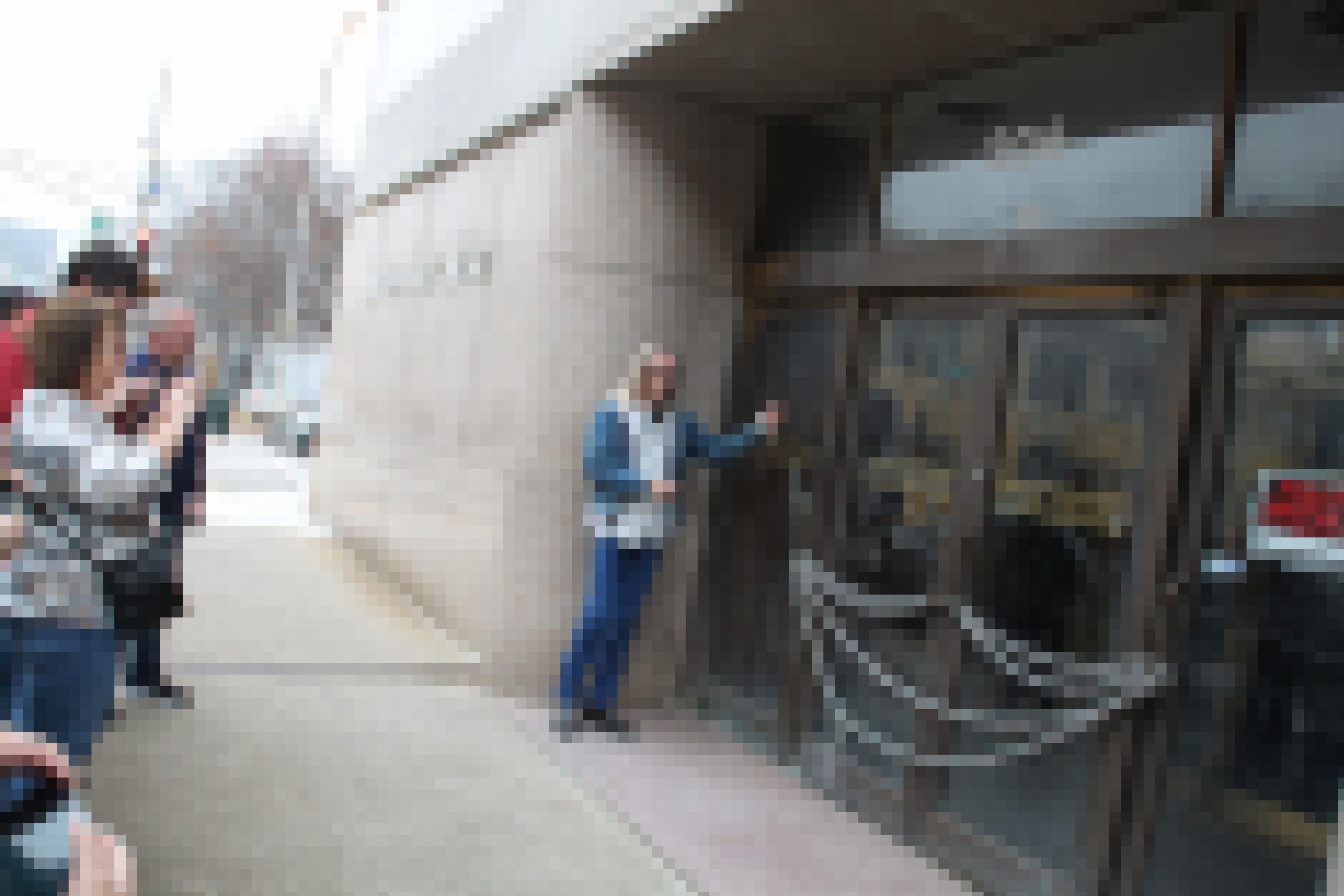 Ein Mann steht vor einer Glastür, daneben Schaulustige mit gezückten Handys.