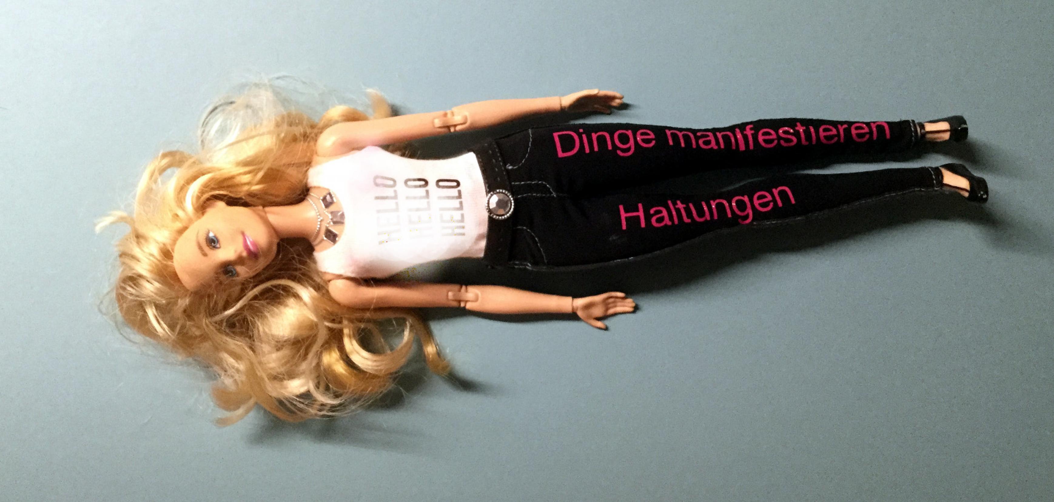 Barbie mit Beschriftung „Dinge manifestieren Haltung“