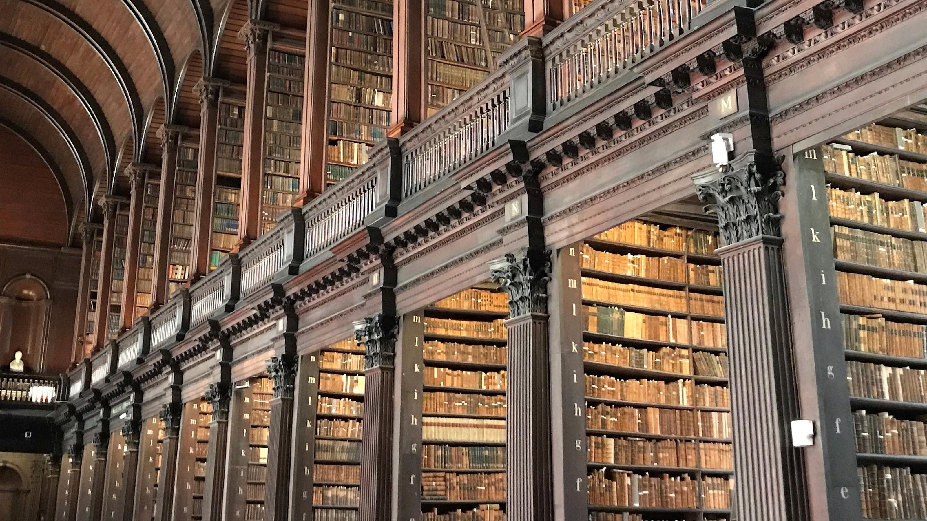 Ein hoher Saal mit zahlreichen Bücherregalen, gefüllt mit kostbaren Büchern. Das Trinity College in Dublin hat eine der ehrwürdigsten Bibliotheken der Welt.