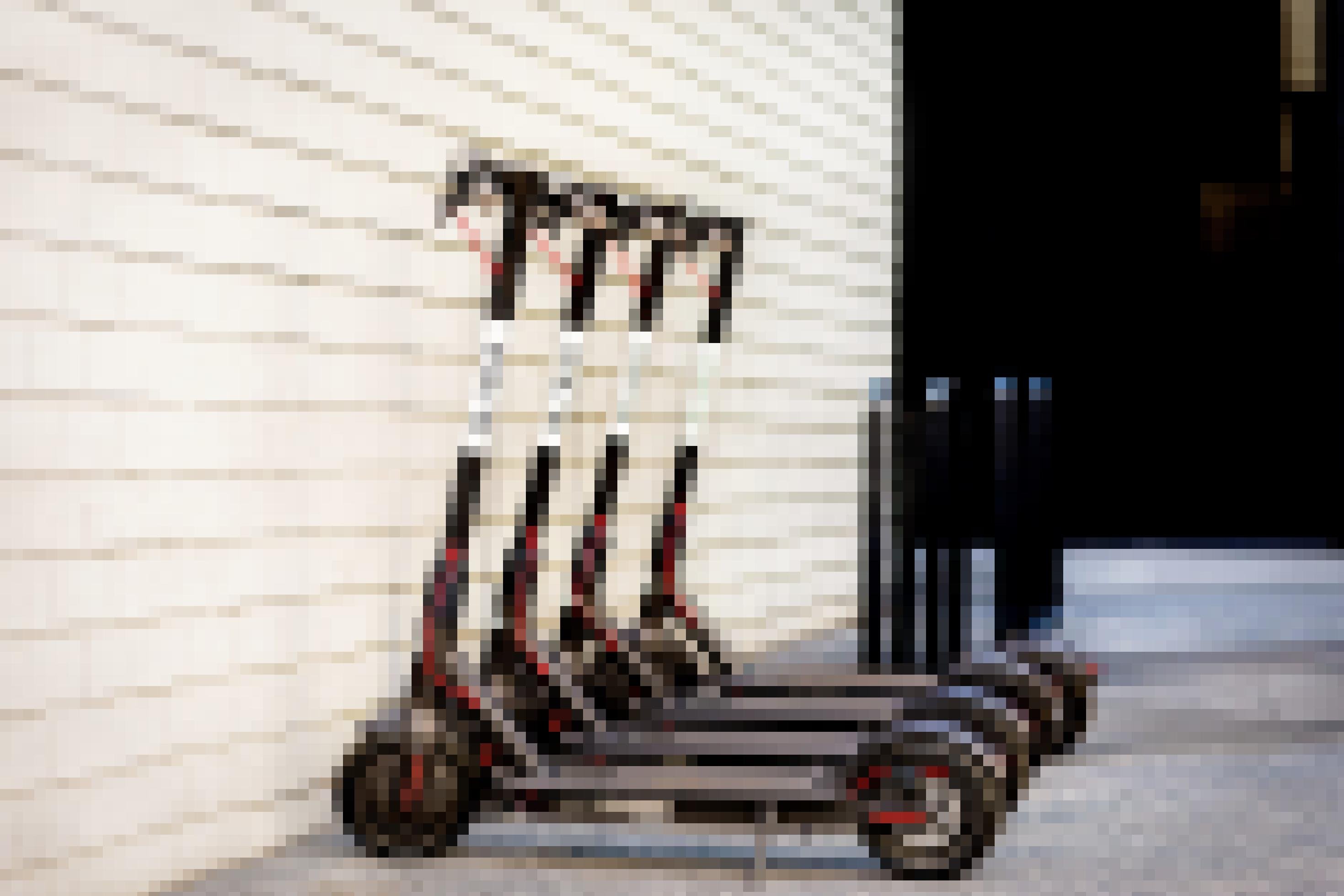 Schwarze E-Scooter mit roten Applikationen werden vor einer Hauswand aufgereiht präsentiert.