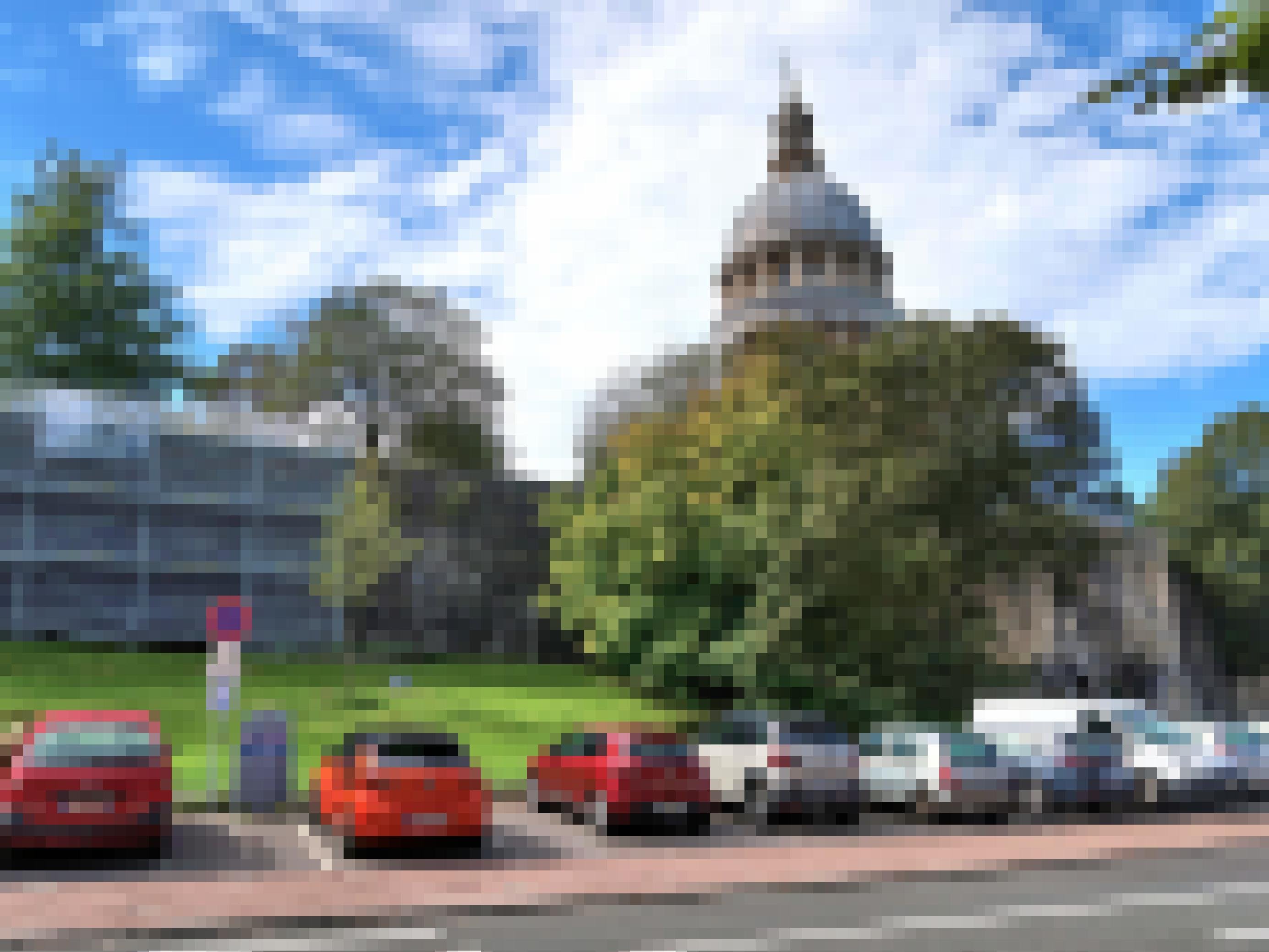 Mehrere Autos parken neben einer Straße. Im Hintergrund ist eine Kathedrale zu sehen.