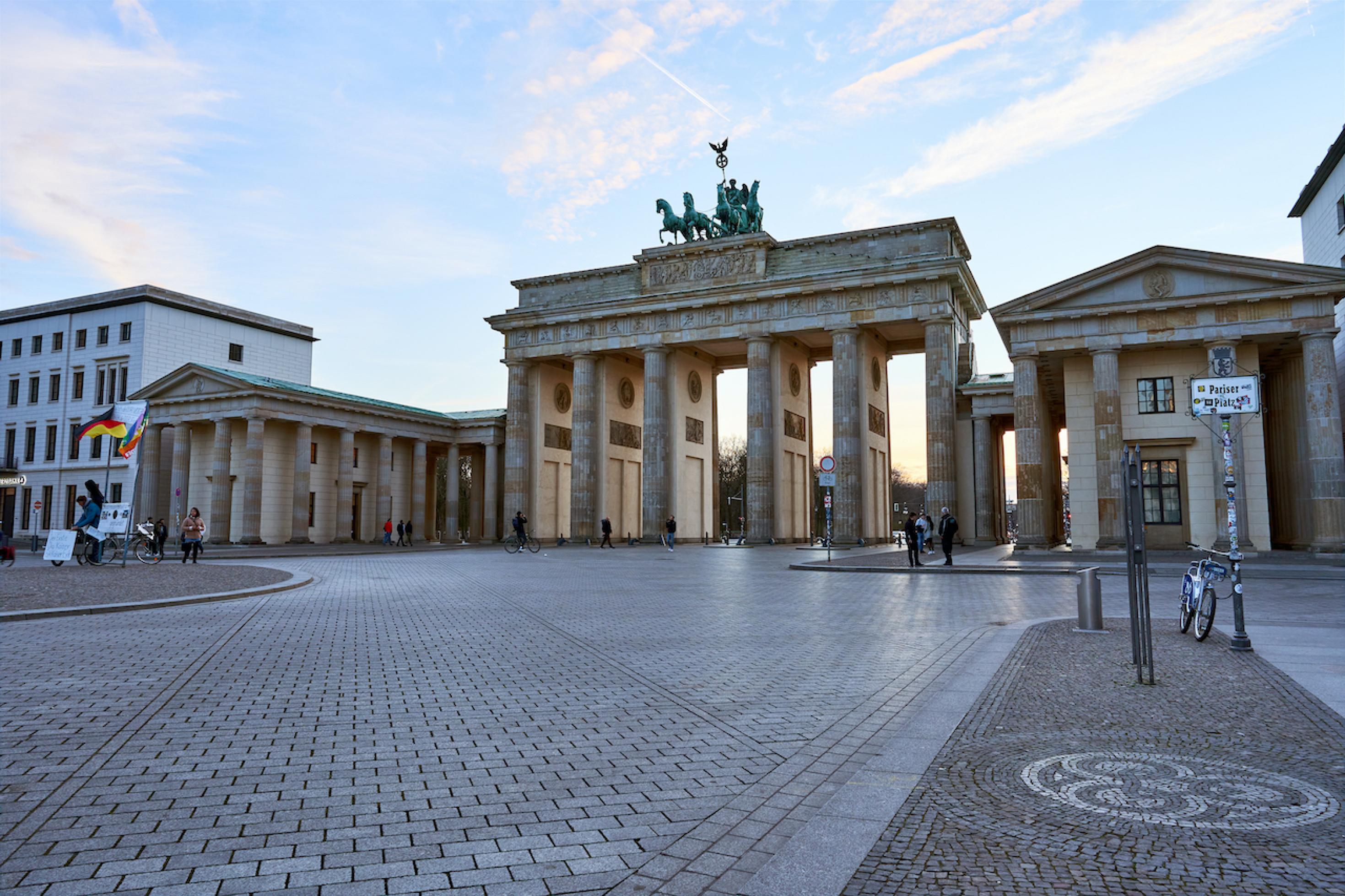 Das Bild zeigt das Brandenburger Tor. Der Vorplatz ist fast ganz leer. Rechts steht ein angeschlossenes Fahrrad an einem Straßenschild.