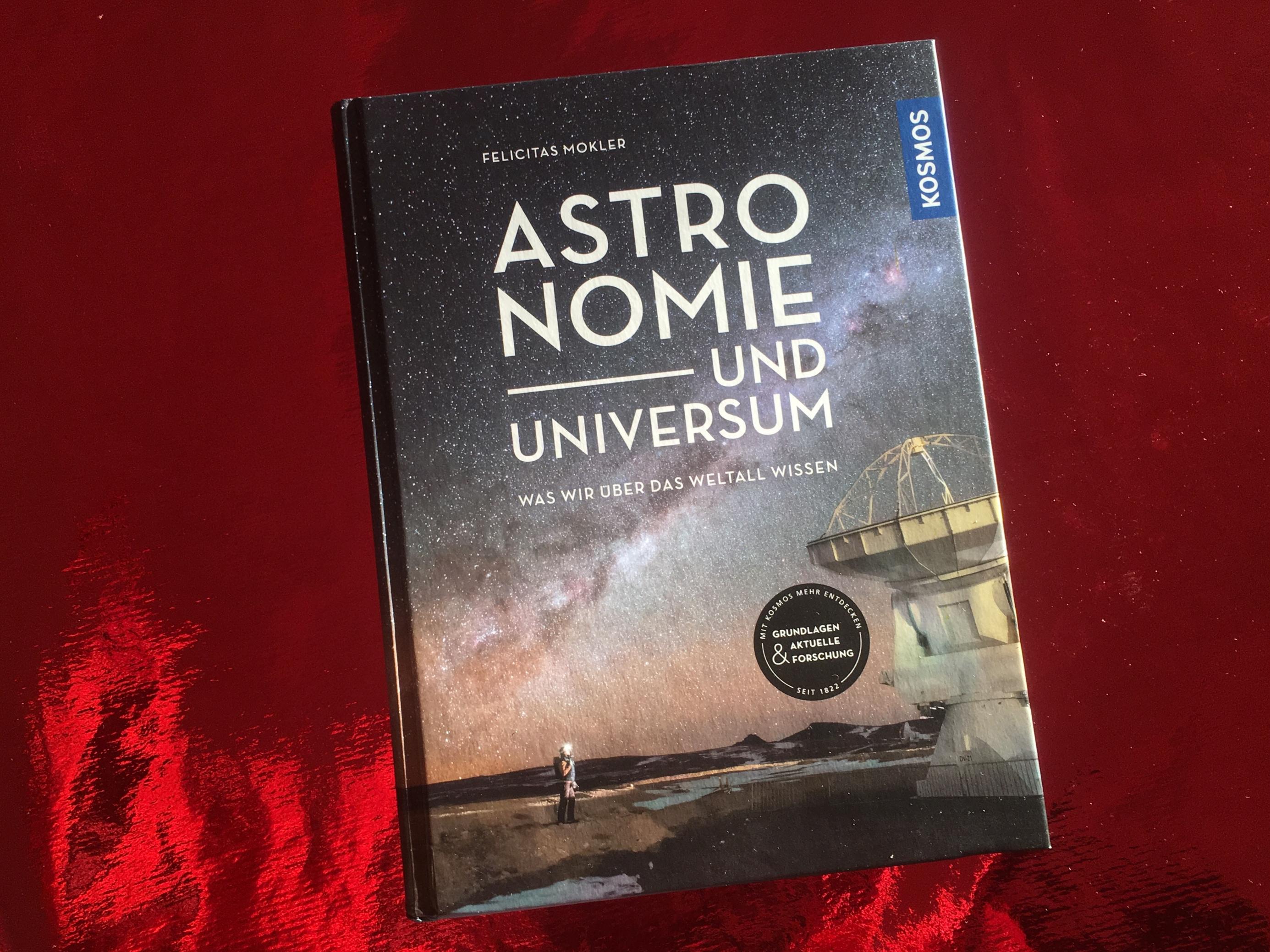 Buch „Astronomie und Universum“ vor rotem Hintergrund