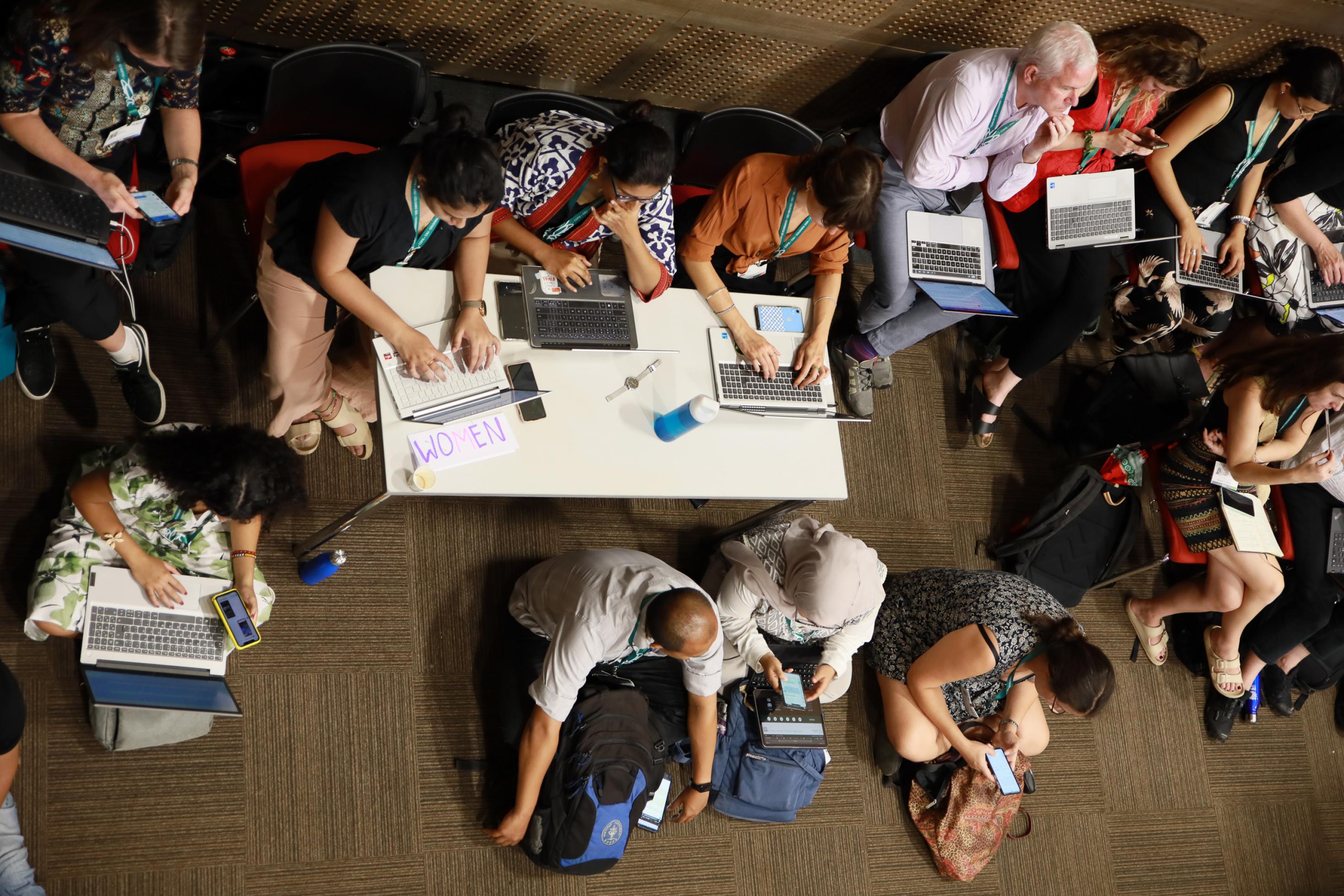 Viele Menschen auf dem Boden sitzend mit Laptops