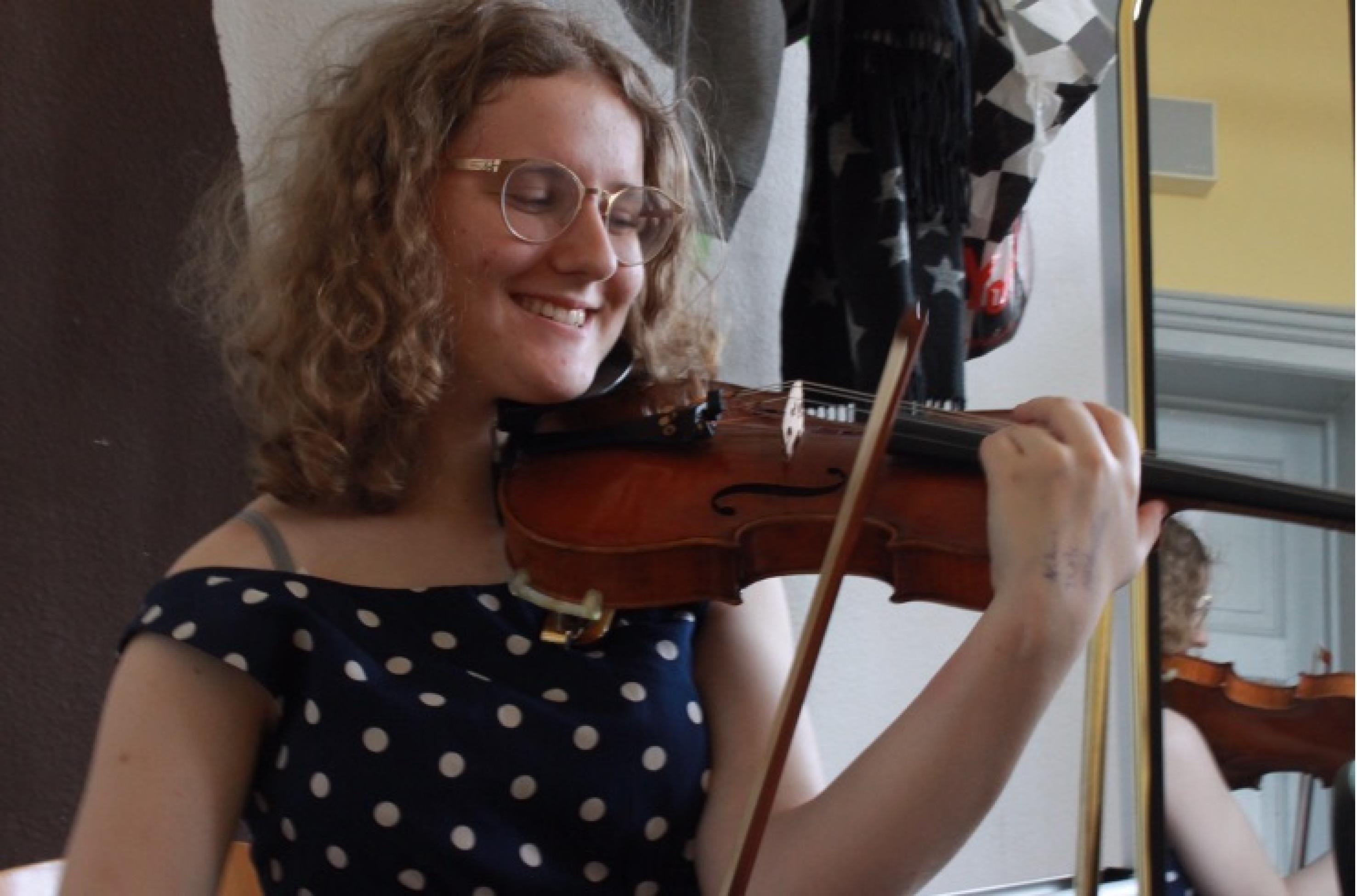 Die Schülerin Charlotte Schneider spielt auf ihrer Geige und lächelt dabei