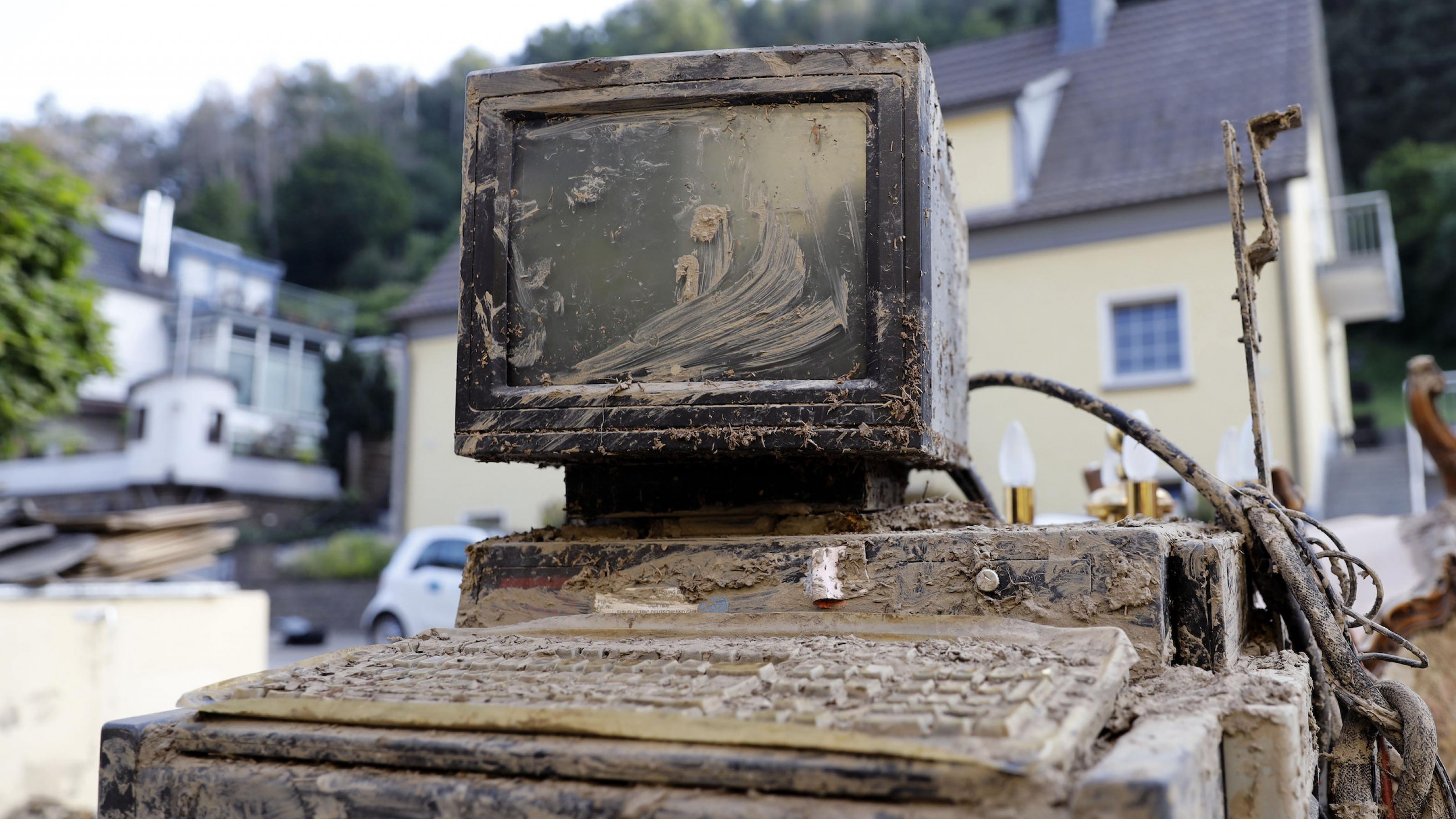 Ein verschlammter Computerbildschirm samt Desktop und Tastatur, der aus dem Flutmüll in der Ortschaft Altenahr geborgen wurde.