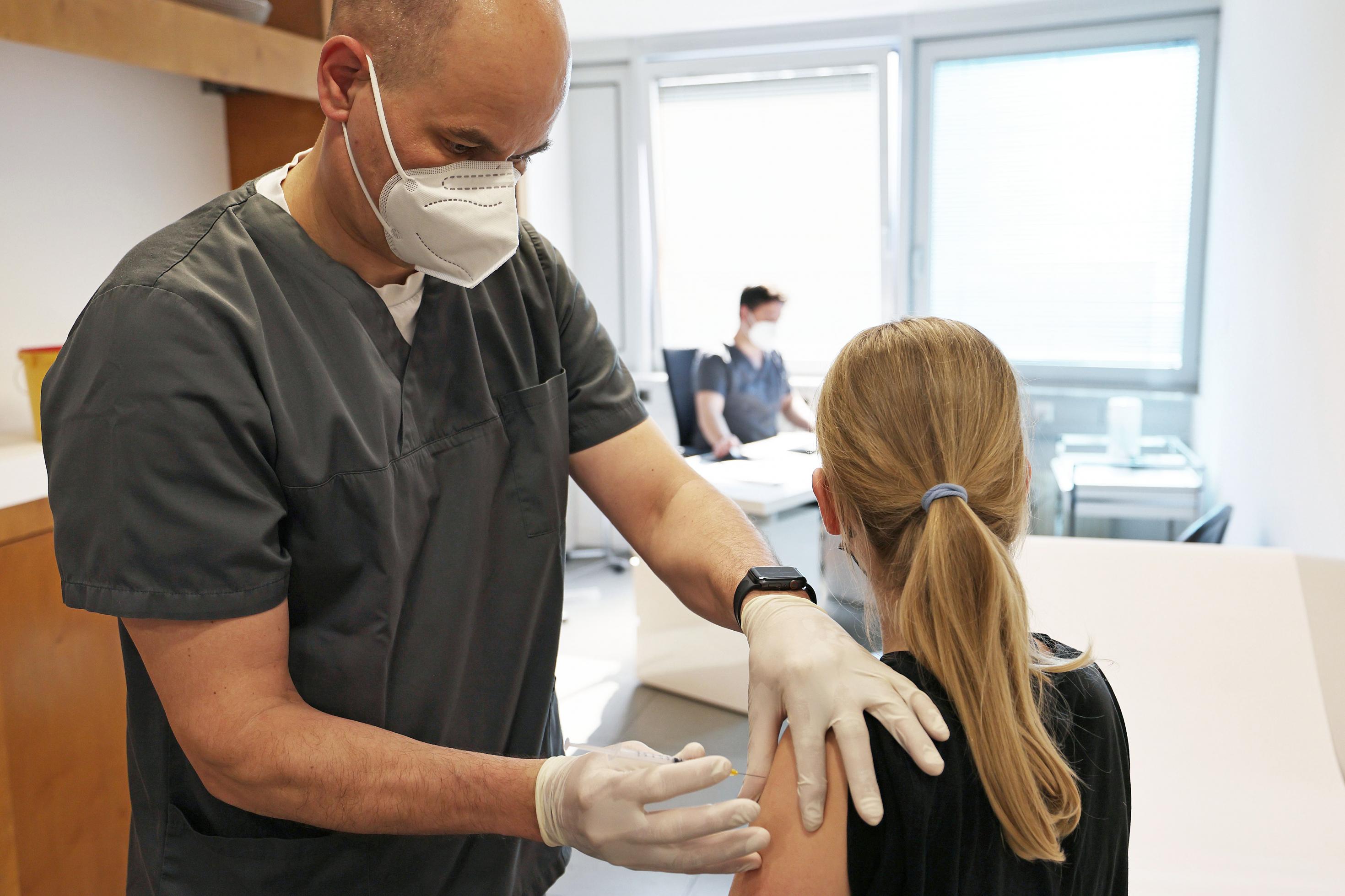 Ein zwölfjähriges Mädchen wird in einer Arztpraxis von dem Hausarzt Tim Koop (l) mit dem Serum von Biontech/Pfizer geimpft. Hausärzte haben begonnen, Kinder und Jugendliche gegen das Coronavirus zu impfen.