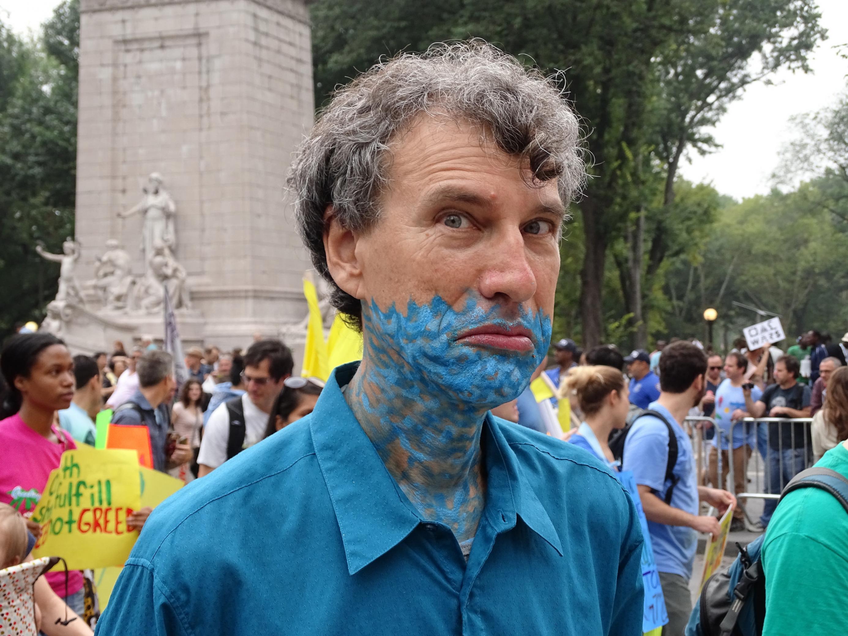 Blaue Striche am Hals symbolisieren Wellen: Das Makeup sagt, das Wasser steht ihm nicht nur bis zum Hals, sondern schon bis zur Oberlippe. Der Blick unterstreicht die Botschaft. Ein Demonstrant beim Peoples Climate March 2014.