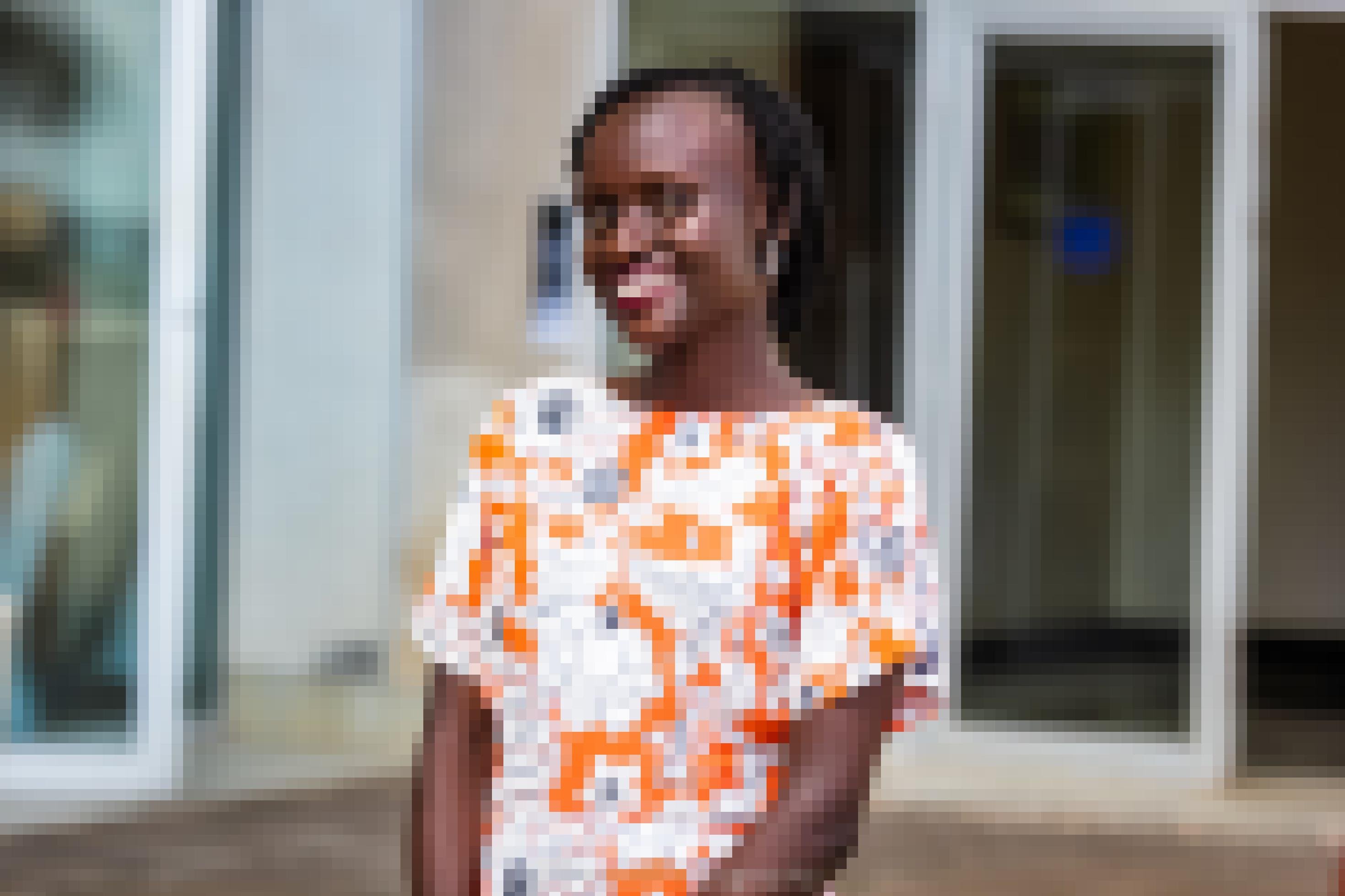Zu sehen ist die 29-jährige ugandische Aktivistin Maria Alesi. Ein Halbkörperporträt, sie trägt ein buntes Kleid und lacht, blickt offen in die Kamera.