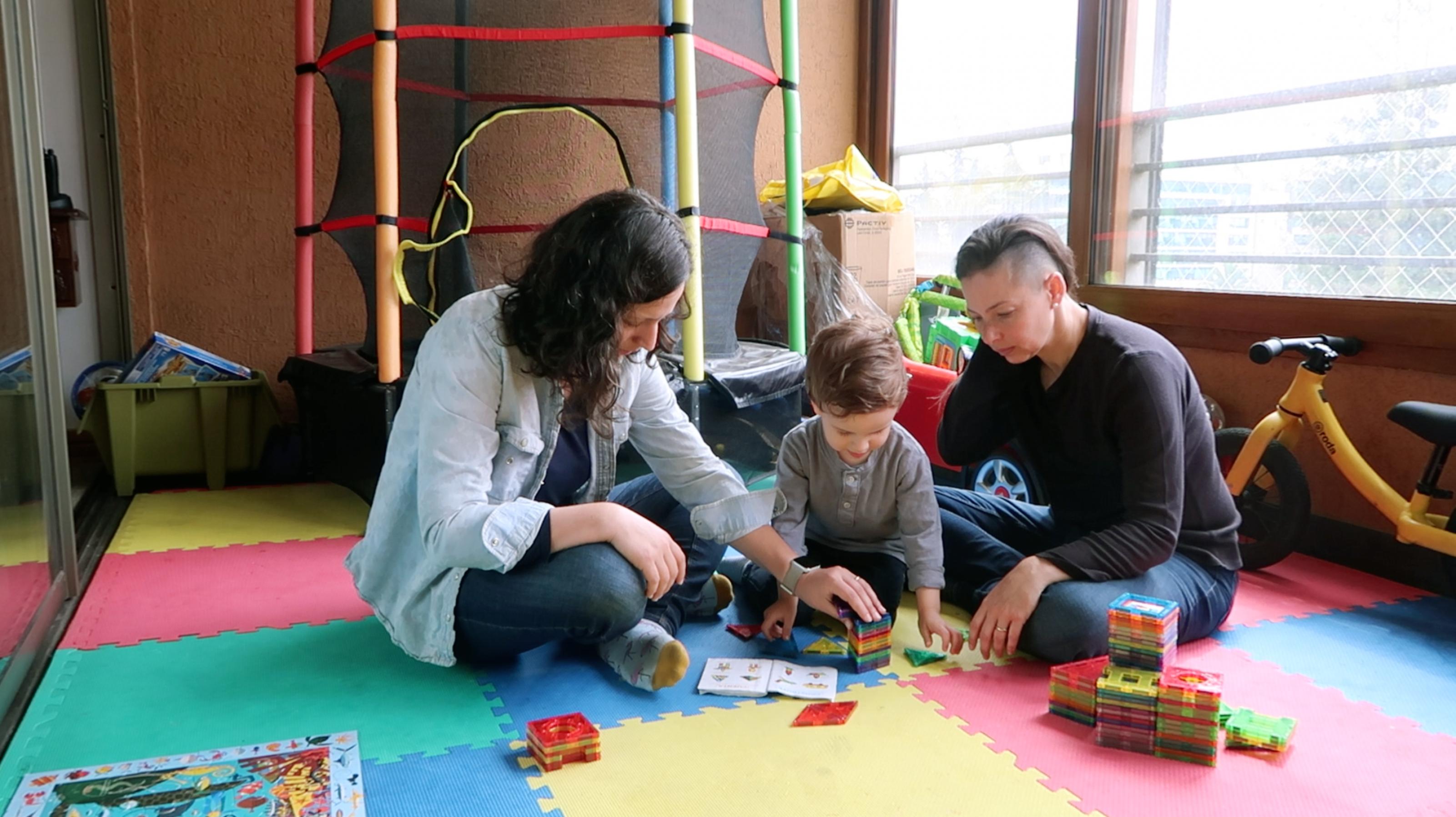 Zwei Frauen spielen mit ihrem Sohn.