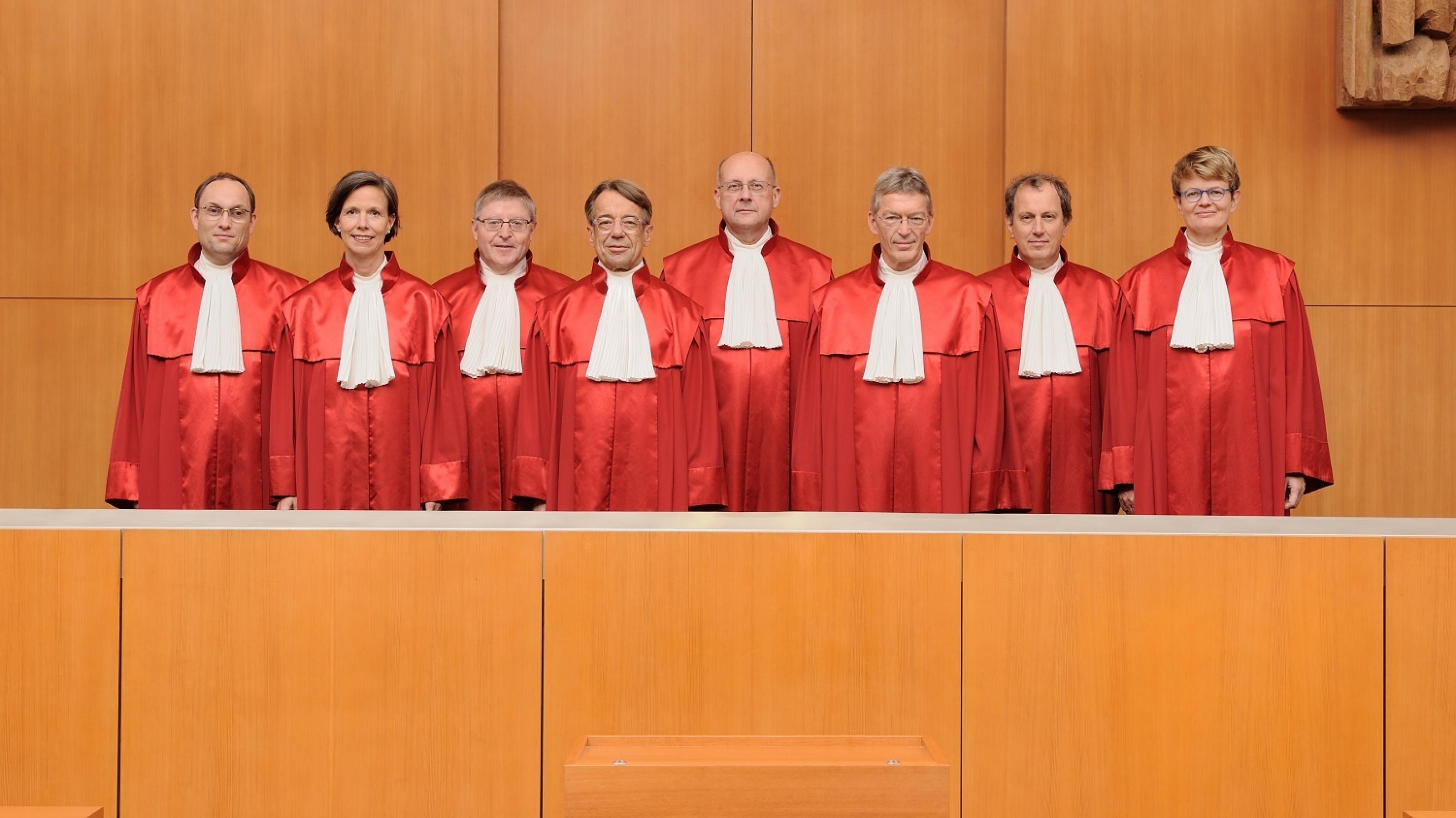 Richter und Richterinnen stehen in roten Roben in einer Reihe