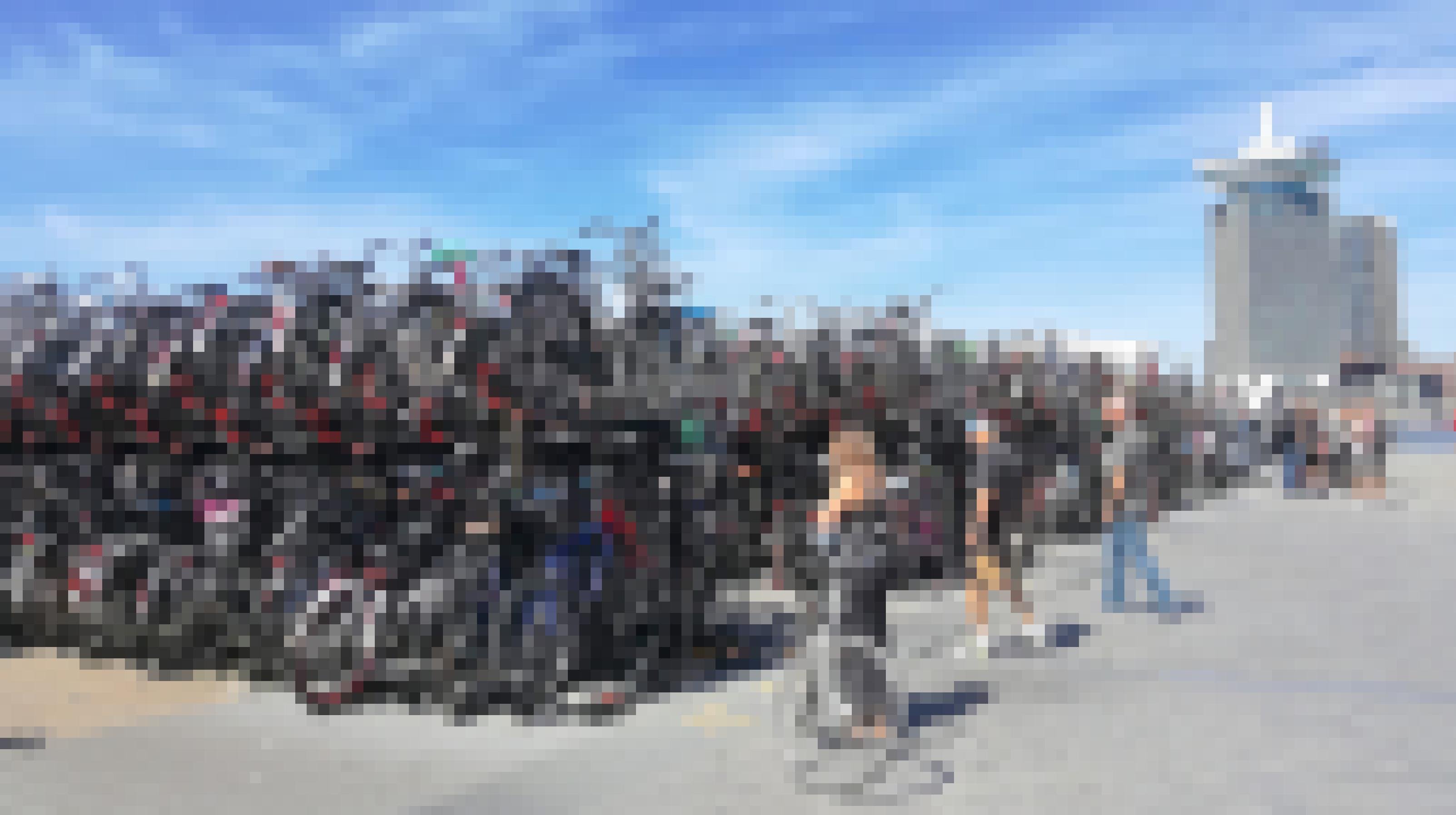 Eine riesige Fahrradabstellanlage am Bahnhof unter blauem Himmel. Menschen laufen vorbei.