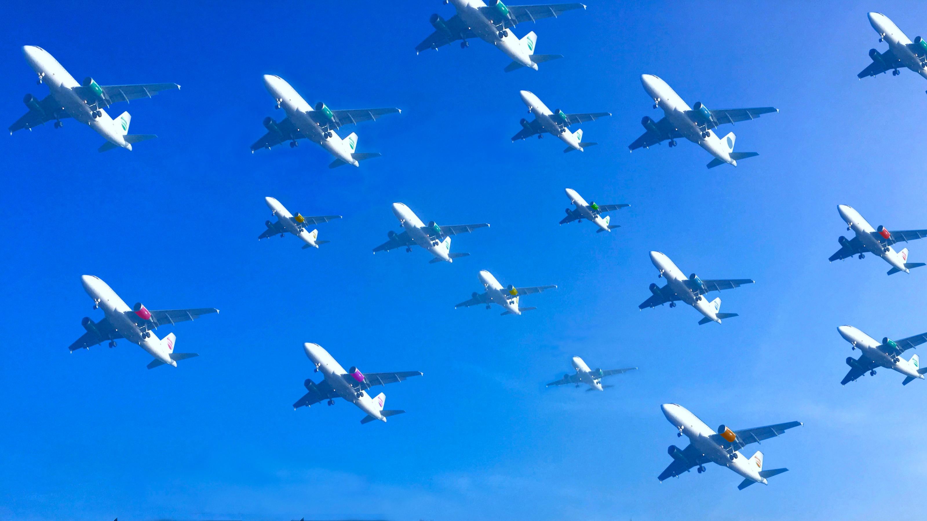 An einem blauen Himmel schwebt in dieser Fotomontage mehr als ein Dutzend Flugzeuge dicht nebeneinander auf den Landeplatz zu.