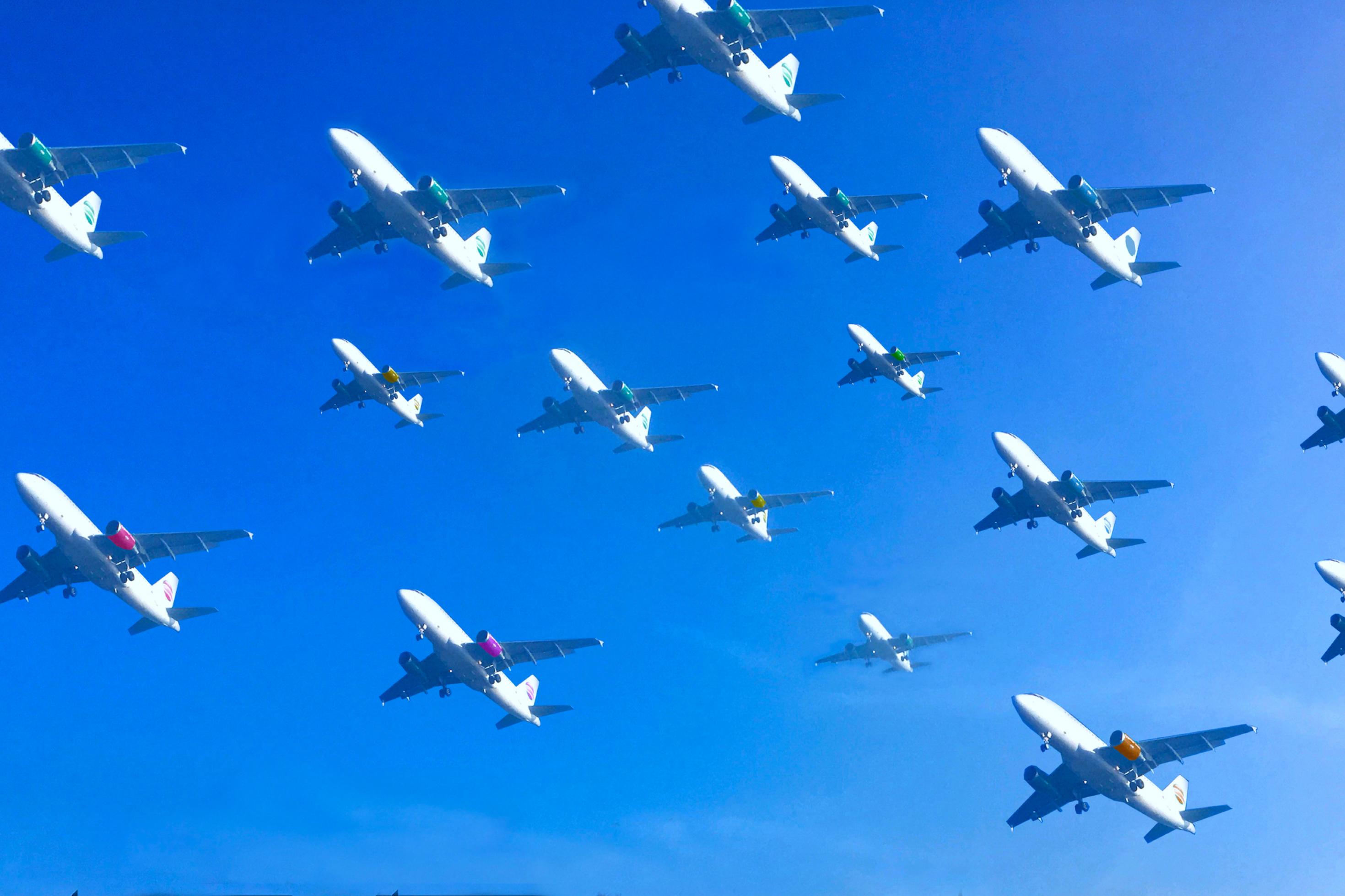 An einem blauen Himmel schwebt in dieser Fotomontage mehr als ein Dutzend Flugzeuge dicht nebeneinander auf den Landeplatz zu.
