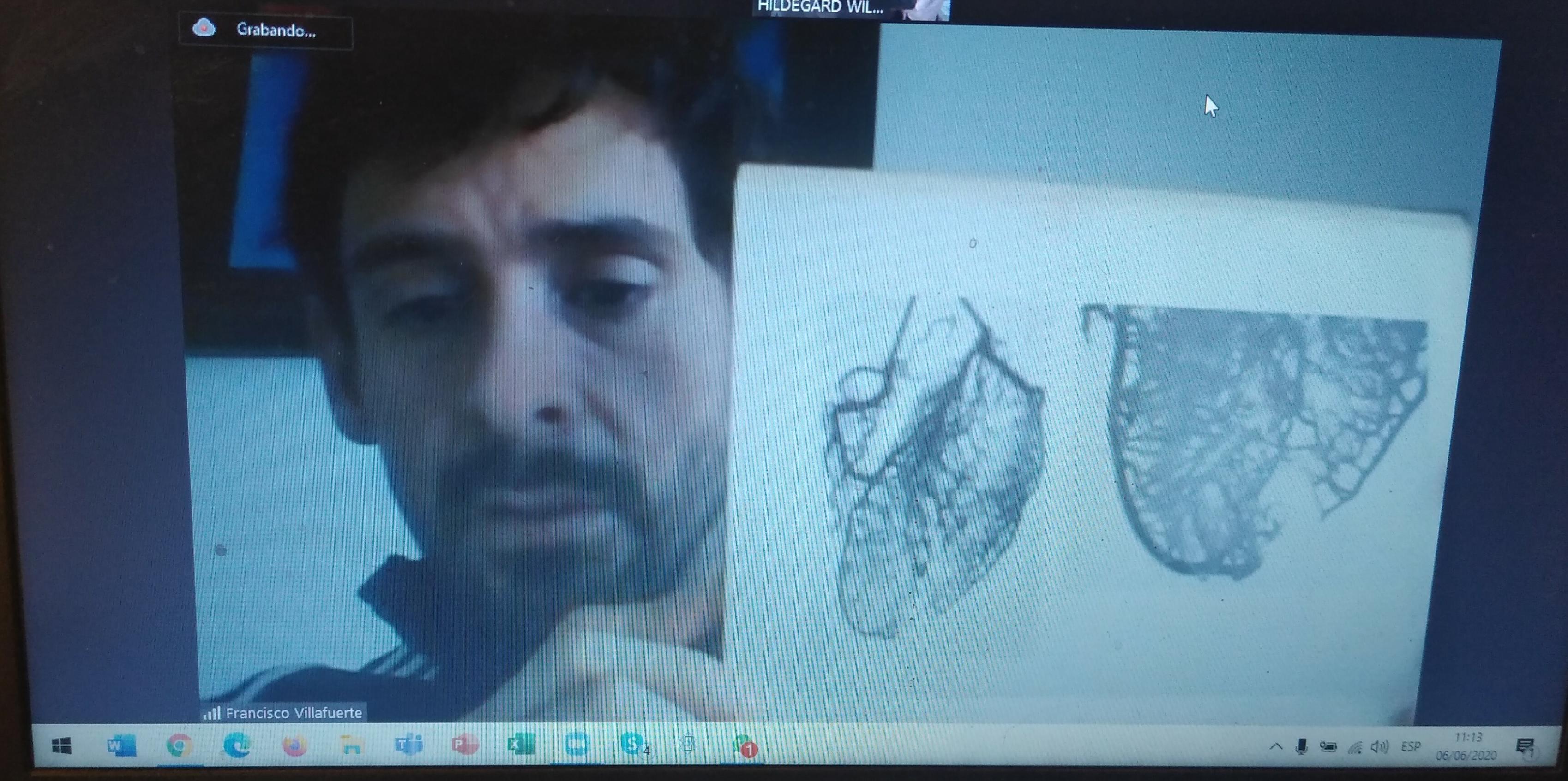 Bildschirmbild. Ein rund 30-jähriger Mann mit schwarzen Haaren hält eine Buchseite in die Bildschirmkamera, auf der das Gefässsystem des Herzens abgebildet ist.