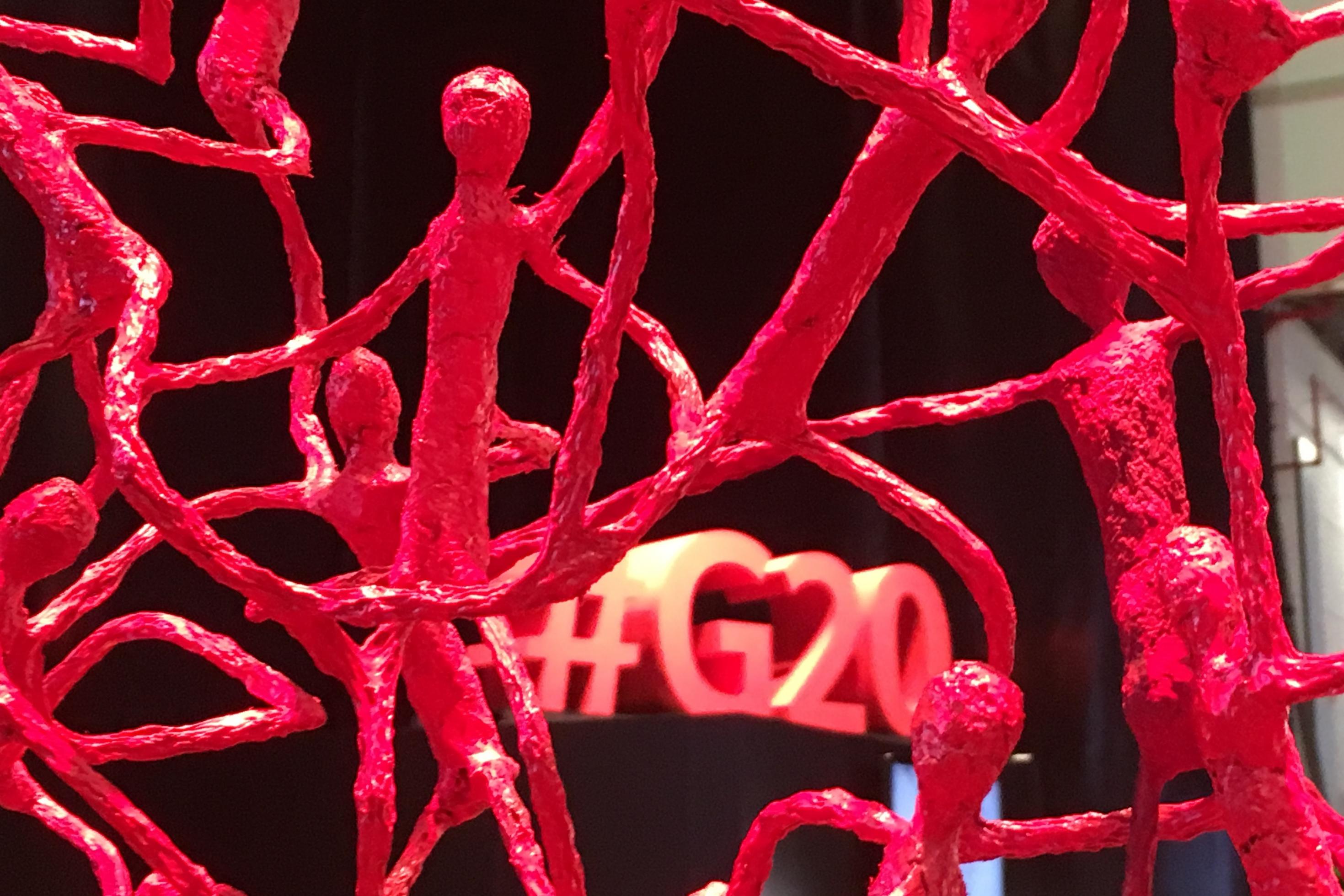 Überall im Hamburger Messezentrum standen Kunstwerke, die dreidimensionale Netzwerke von Menschen zeigen sollten. Hier ist eines in rot und durch die Maschen ist der Schriftzug „#G20“ an der Wand zu sehen.