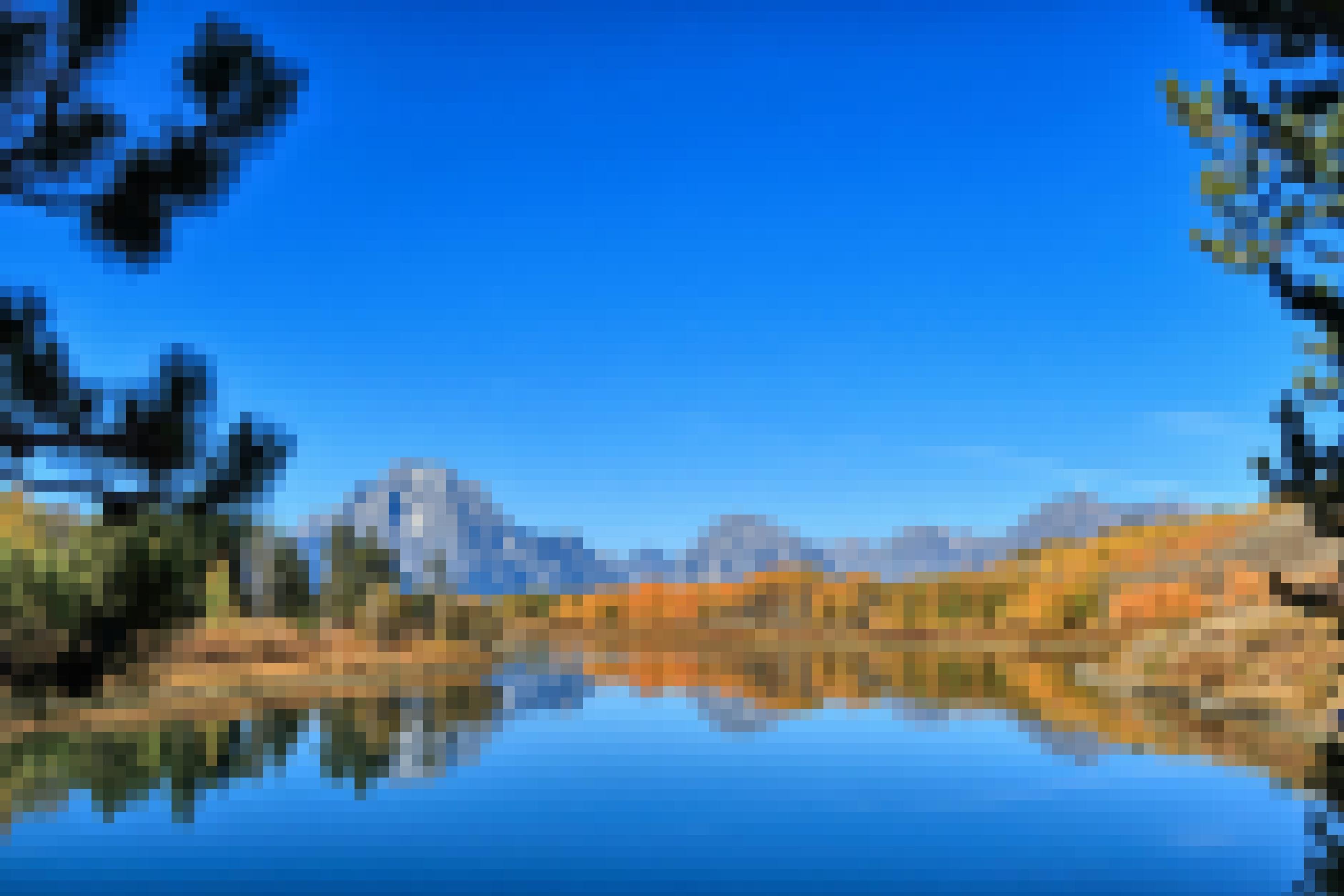 Ein See, im Hintergrund Berge vor blauem Himmel