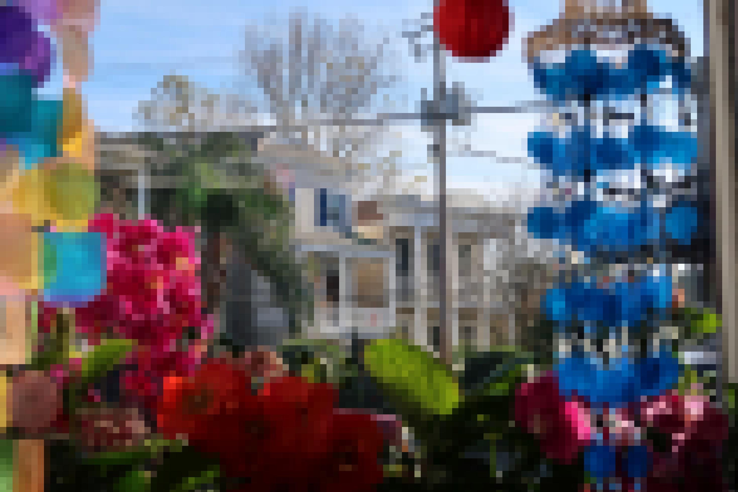 Blick auf Häuser aus einem anderen Haus. Im Vordergrund sind Blumen und bunte Deko zu sehen.