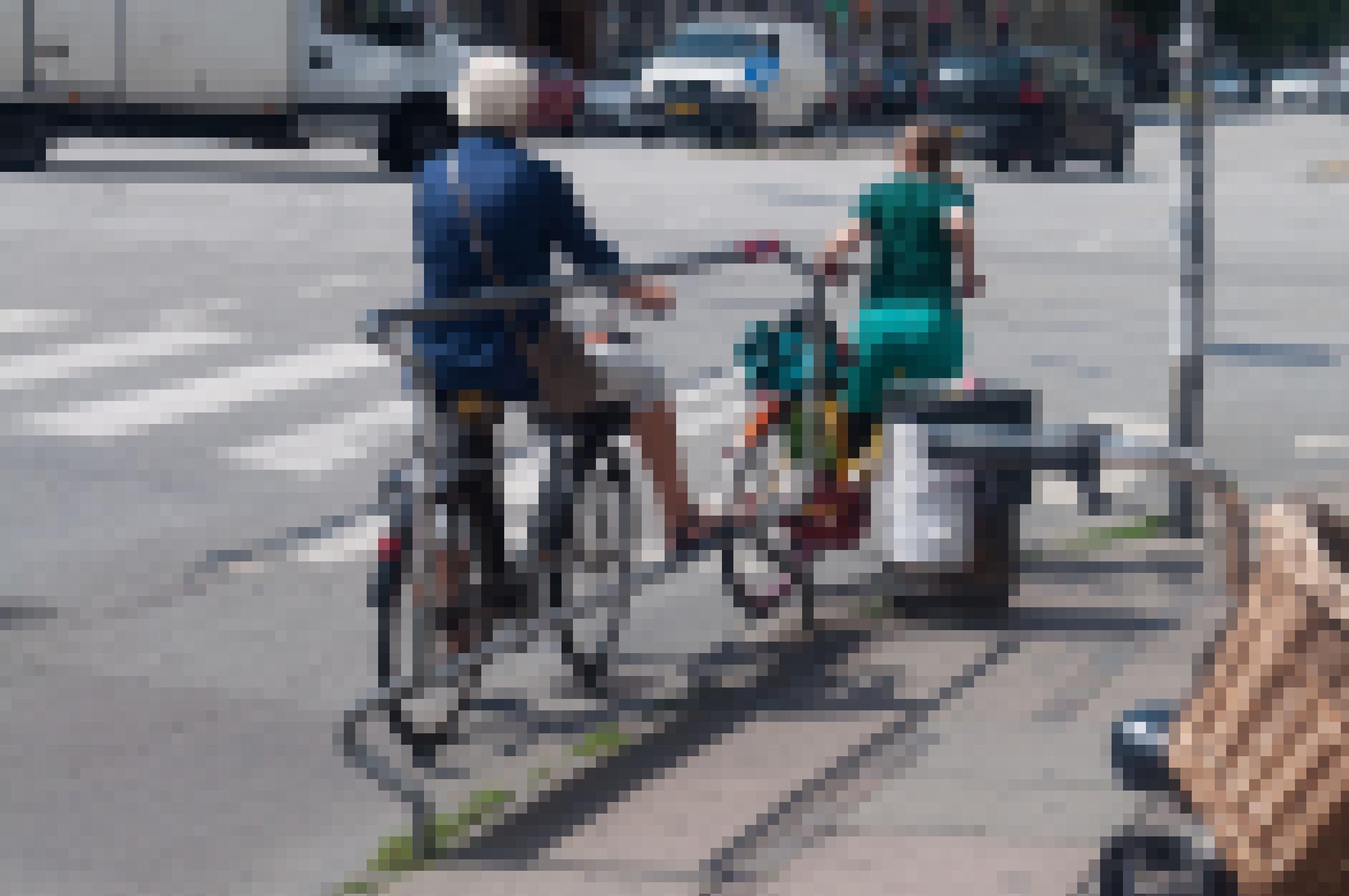 Eine junge Frau hält sich an einer Haltestangen fest. Auf diese Weise muss sie nicht vom Fahrrad absteigen.