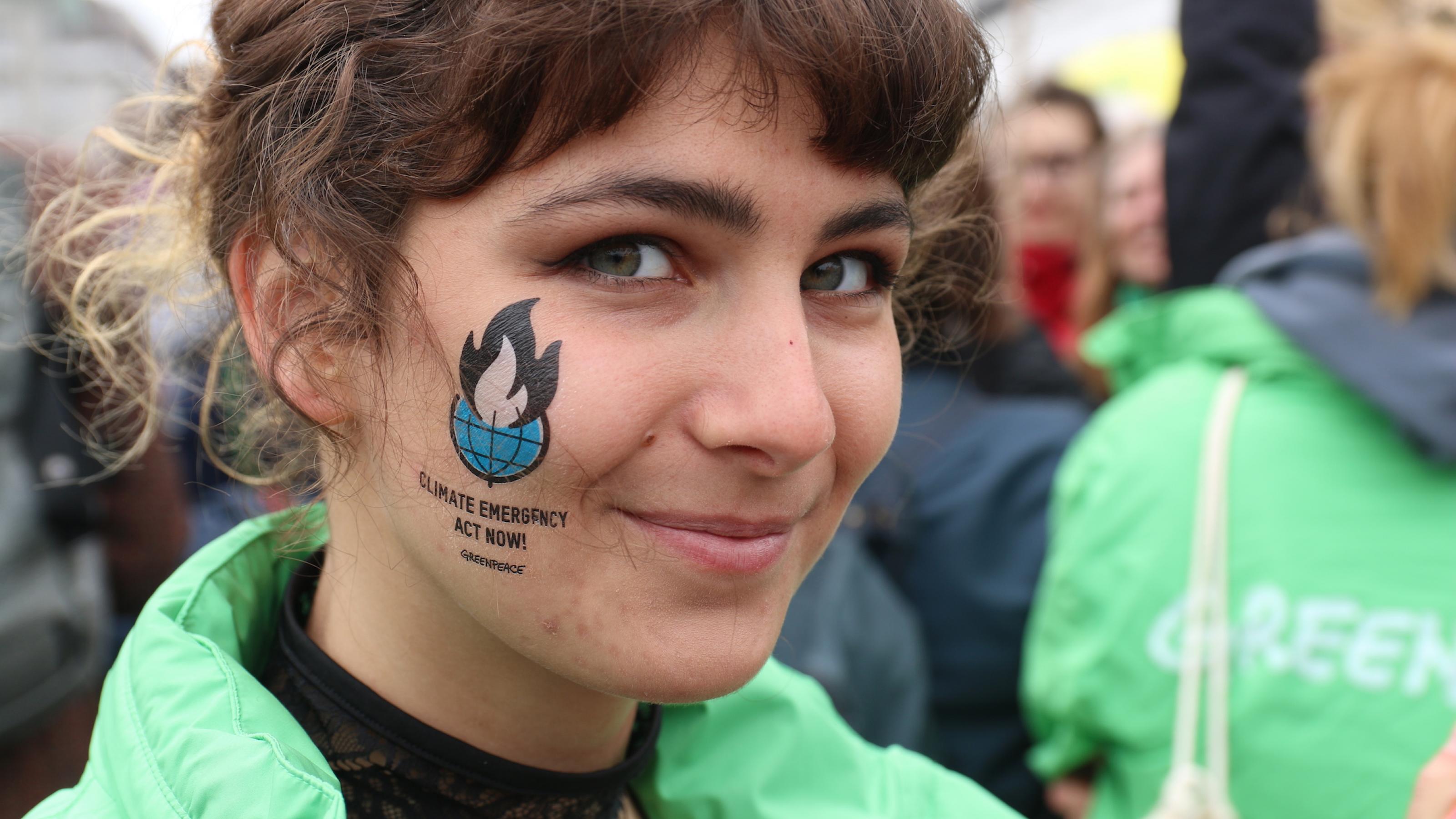 Das Tattoo auf der Wange dieser Hamburger Klimaaktivistin spricht von einem Klimanotstand.