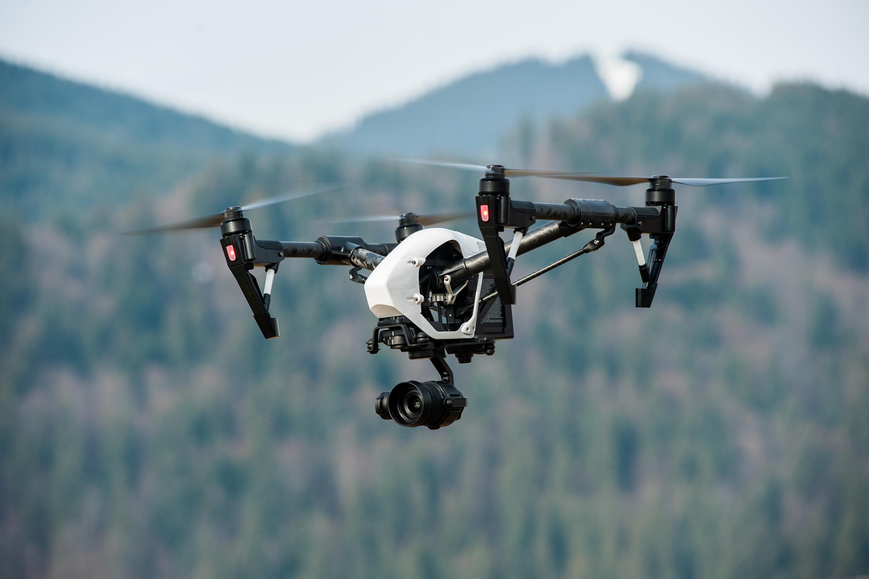 Eine Drohne mit Kamera über einer gebirgigen Landschaft als Symbolbild für automatisierte Grenzüberwachung.
