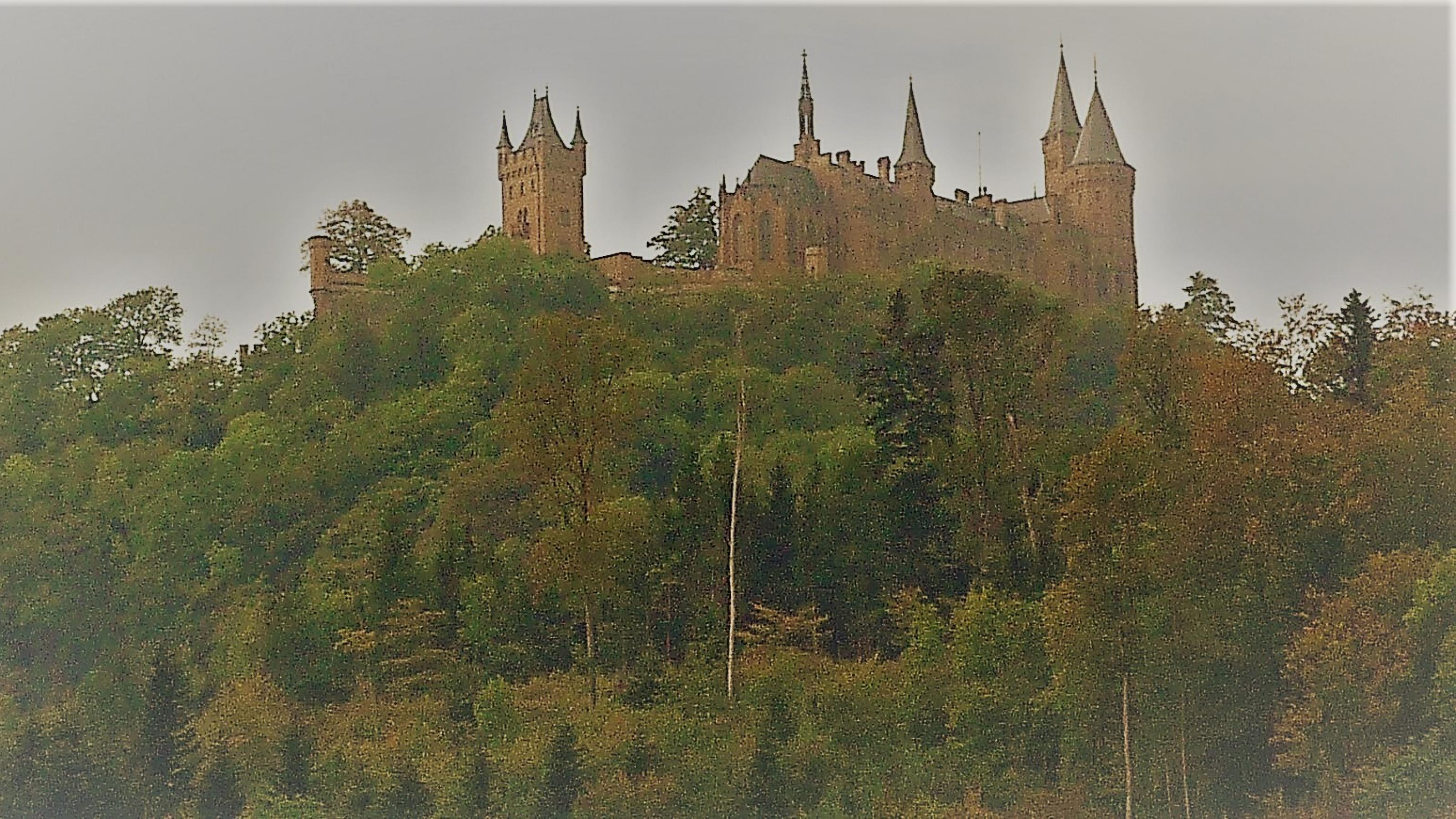 Über den steilen, dicht bewaldeten Hängen südlich der Ortschaft Boll ragen die Giebel und Zinnen der turmbewehrten Burg auf.