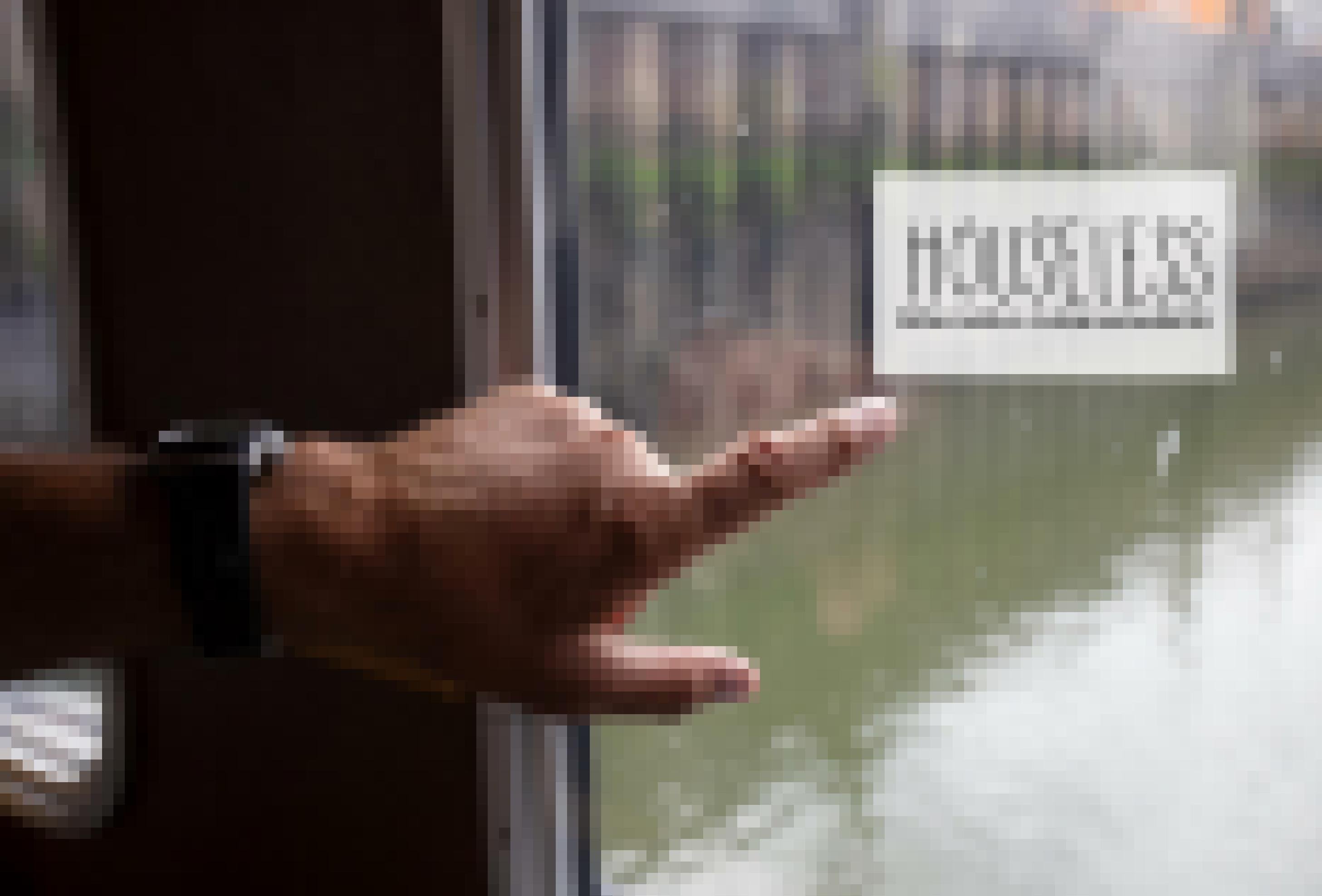 Eine Hand deutet auf ein Fenster, hinter dem Wasser und das Logo von Houseless zu sehen ist.