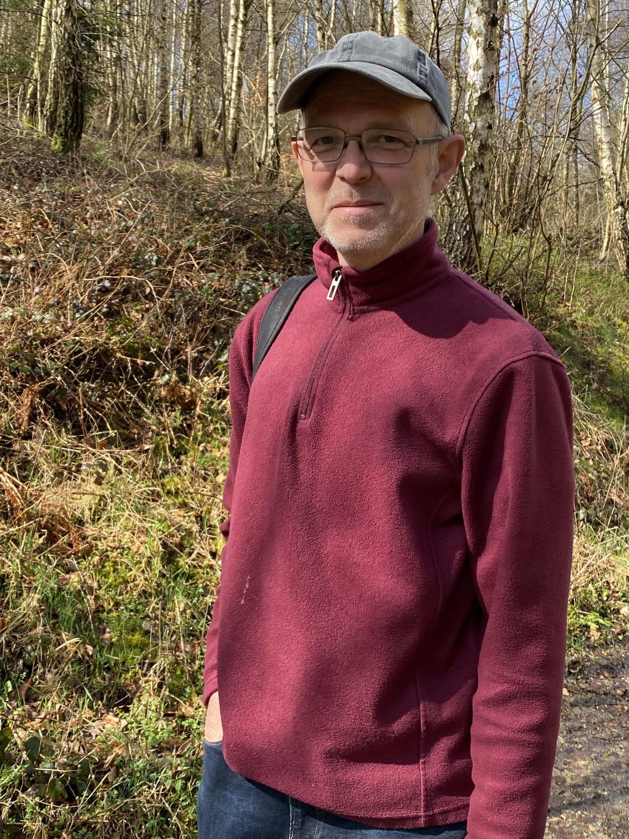 Lutz Dalbeck ist ein schmaler, groß gewachsener Mann mit einem Baseball-Cap, Brille und einem kleinen grauen Bart. Etwa Mitte, Ende 50.