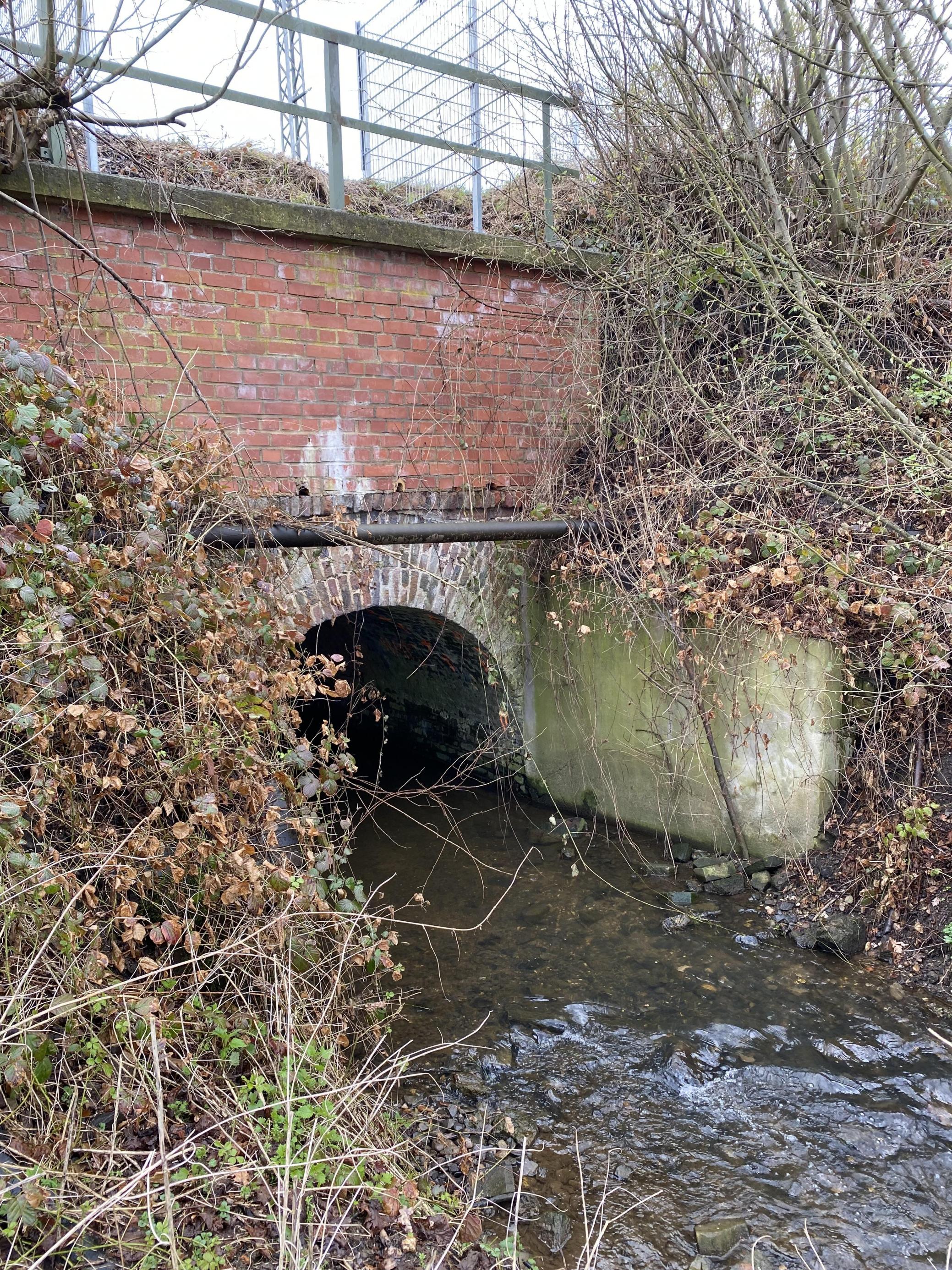 Ein Bahndamm: Steinbrücke über einen kleinen Bach.