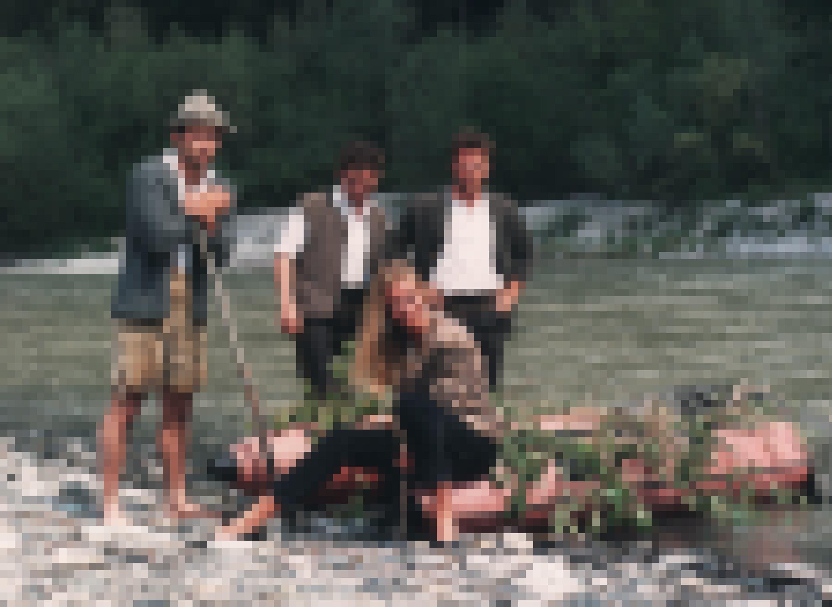 Schlauchboot am Flussufer mit Pflanzen dekoriert, drei Männer und eine Frau