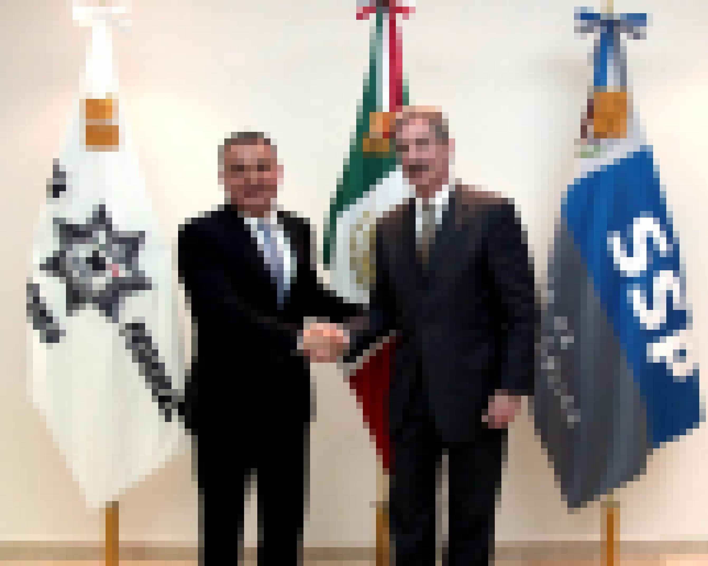 Zwei Männer schütteln sich vor Fahnen die Hand: der mexikanische Ex-Sicherheitsminister García Luna und der ehemalige US-Generalstaatsanwalt James Cole