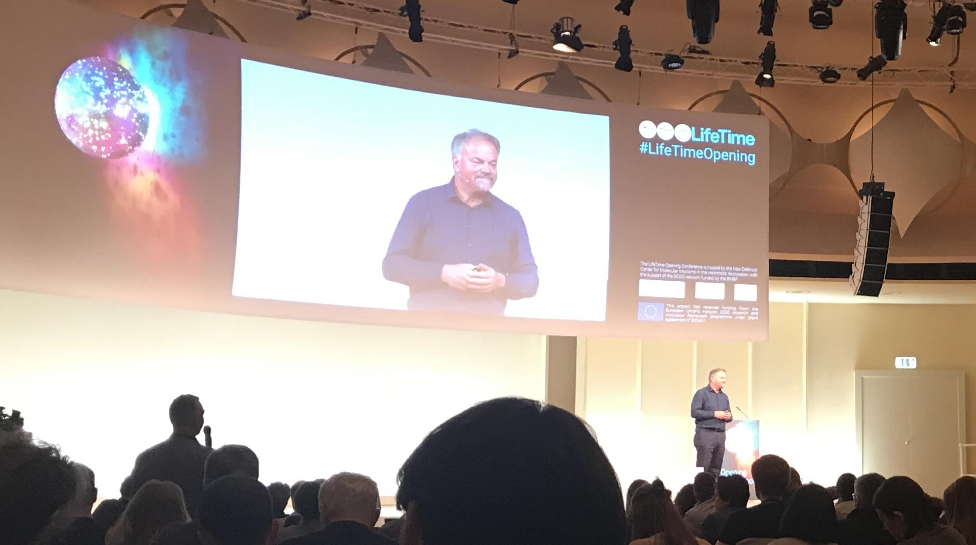 Der Zellbiologe Jürgen Knoblich steht auf dem Podium des Kongresszentrums Berlin und hält einen Vortrag.