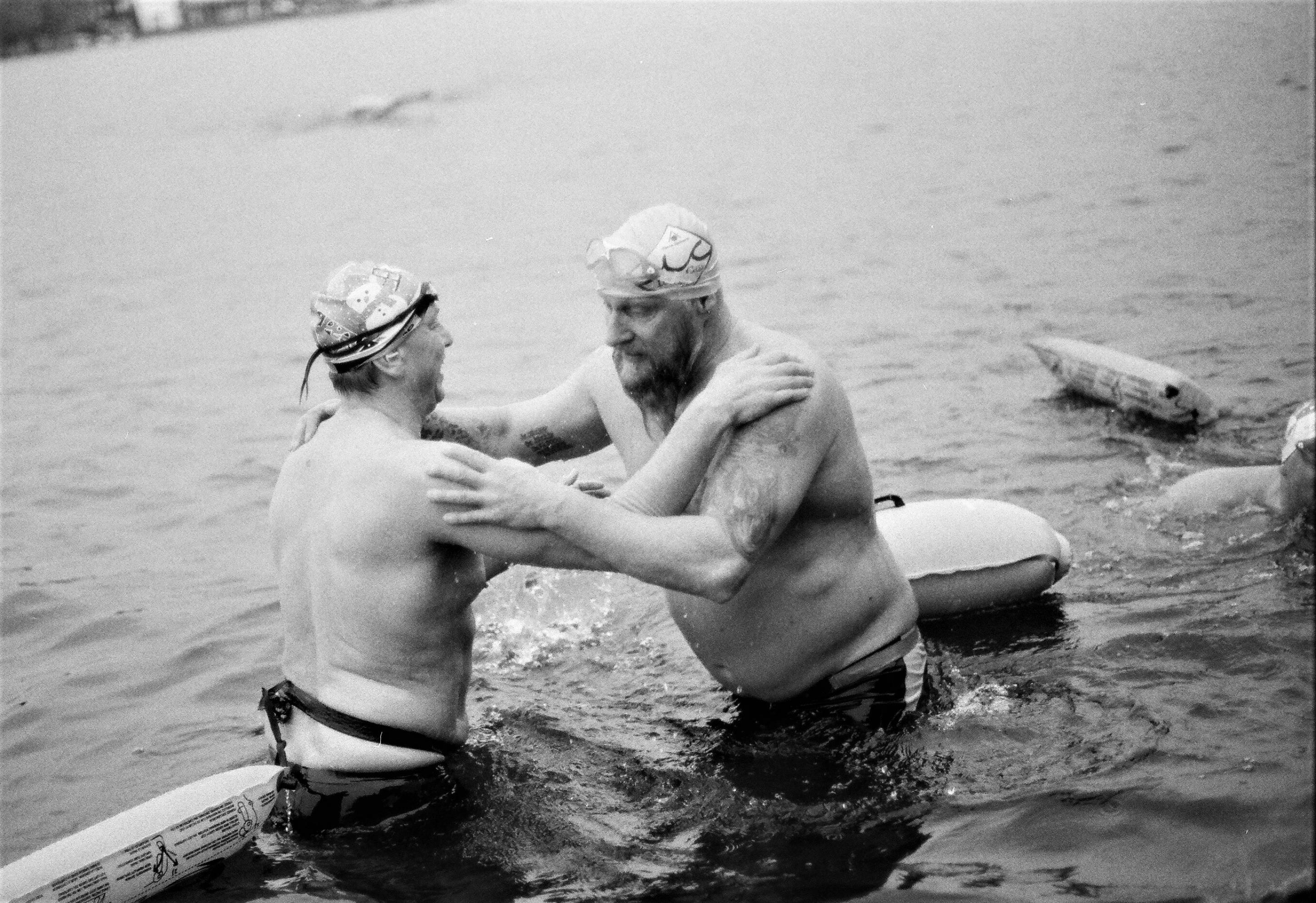 Zwei Männer nur in Badehose im eiskalten Wasser stehend.
