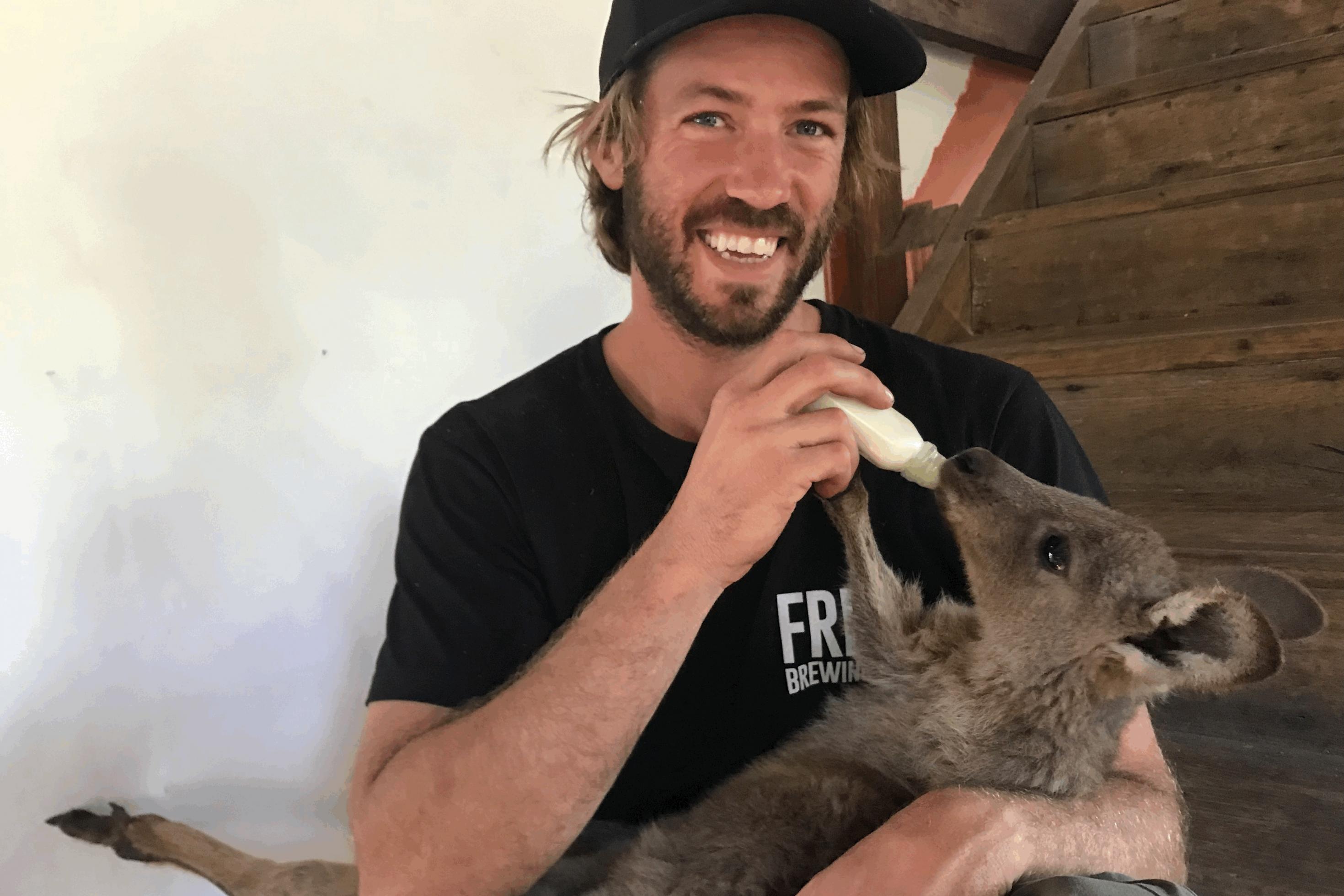 Der 35-jährige Aaron Shanks hält das Känguru-Waise auf dem Schoss und gibt ihm Milchersatz aus einem Fläschchen.