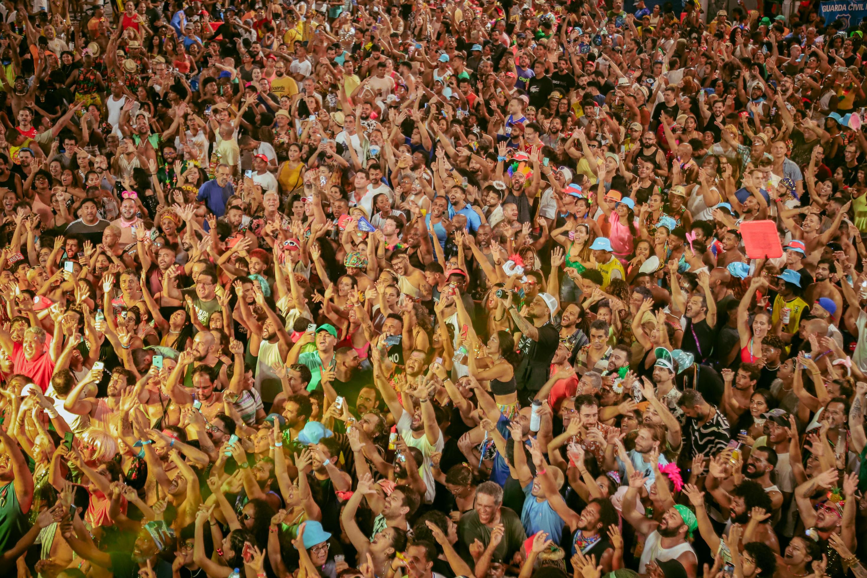 Eine große Menschenmenge von Karnevalisten in Bahia mit ihren Händen in die Höhe., von oben fotografiert.